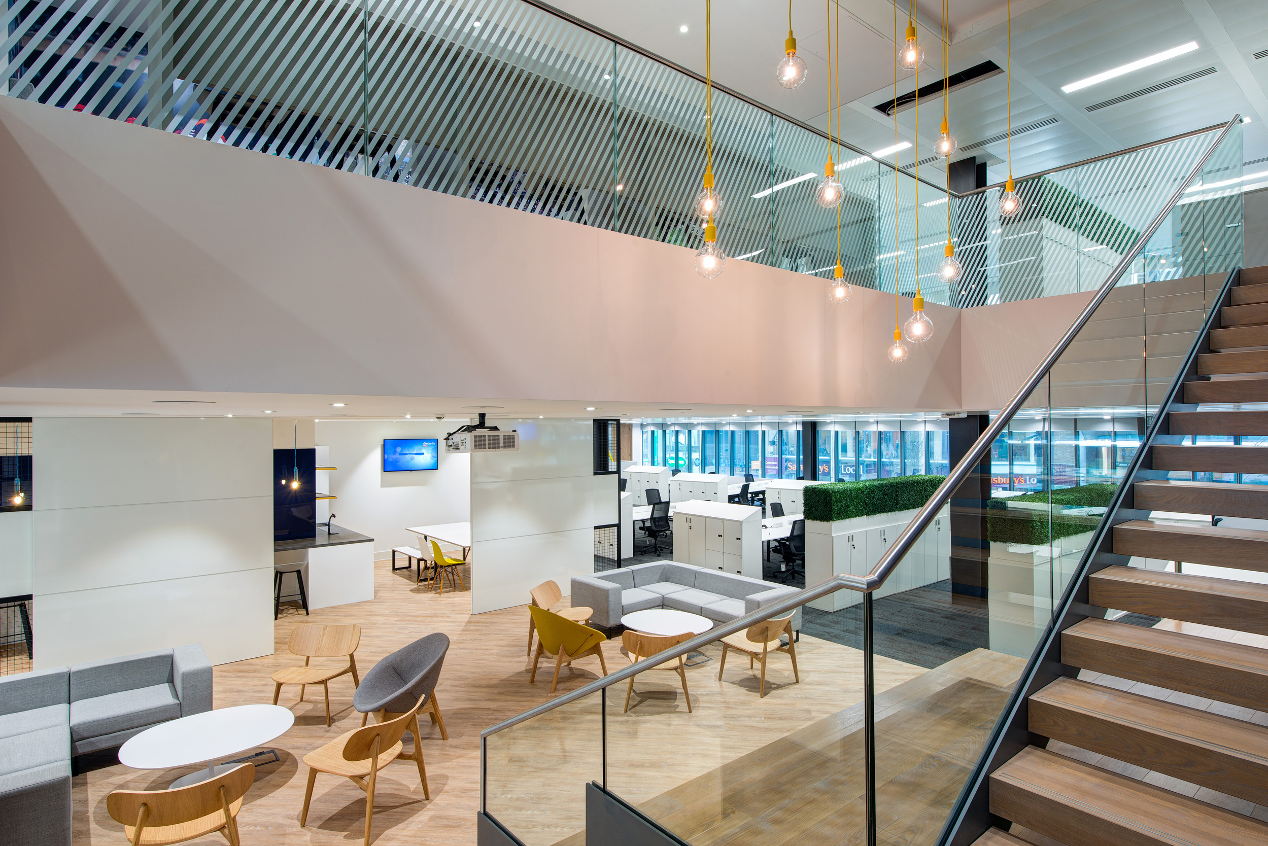 An open-plan workspace at William Hill, designed by Modus Workspace, with collaborative seating, modern lighting fixtures, and a spacious mezzanine for enhanced productivity.