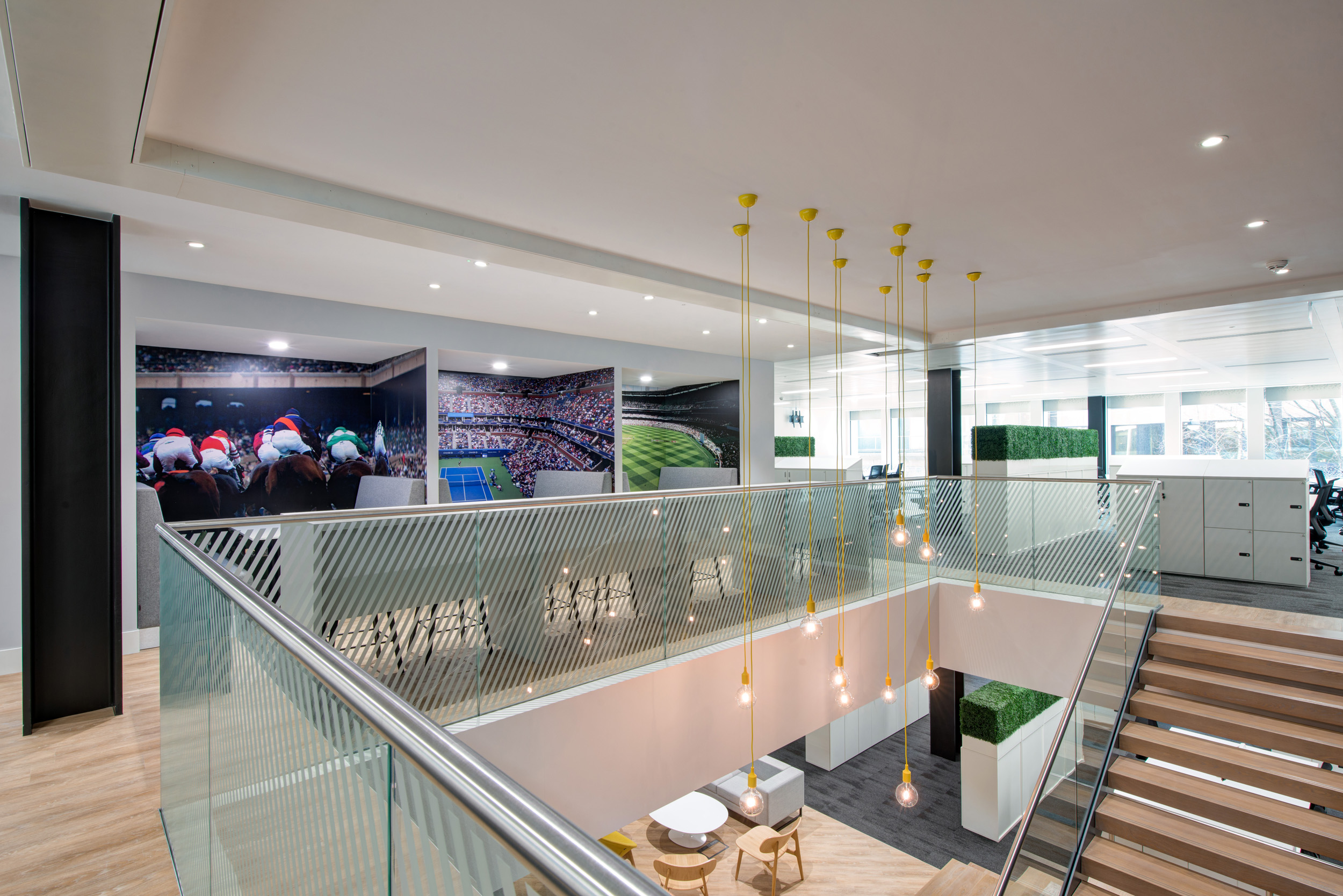 The collaborative workspace at William Hill, designed by Modus Workspace, featuring booth seating, bar-style counters, and vibrant sports-themed wall art, encourages teamwork and innovation.