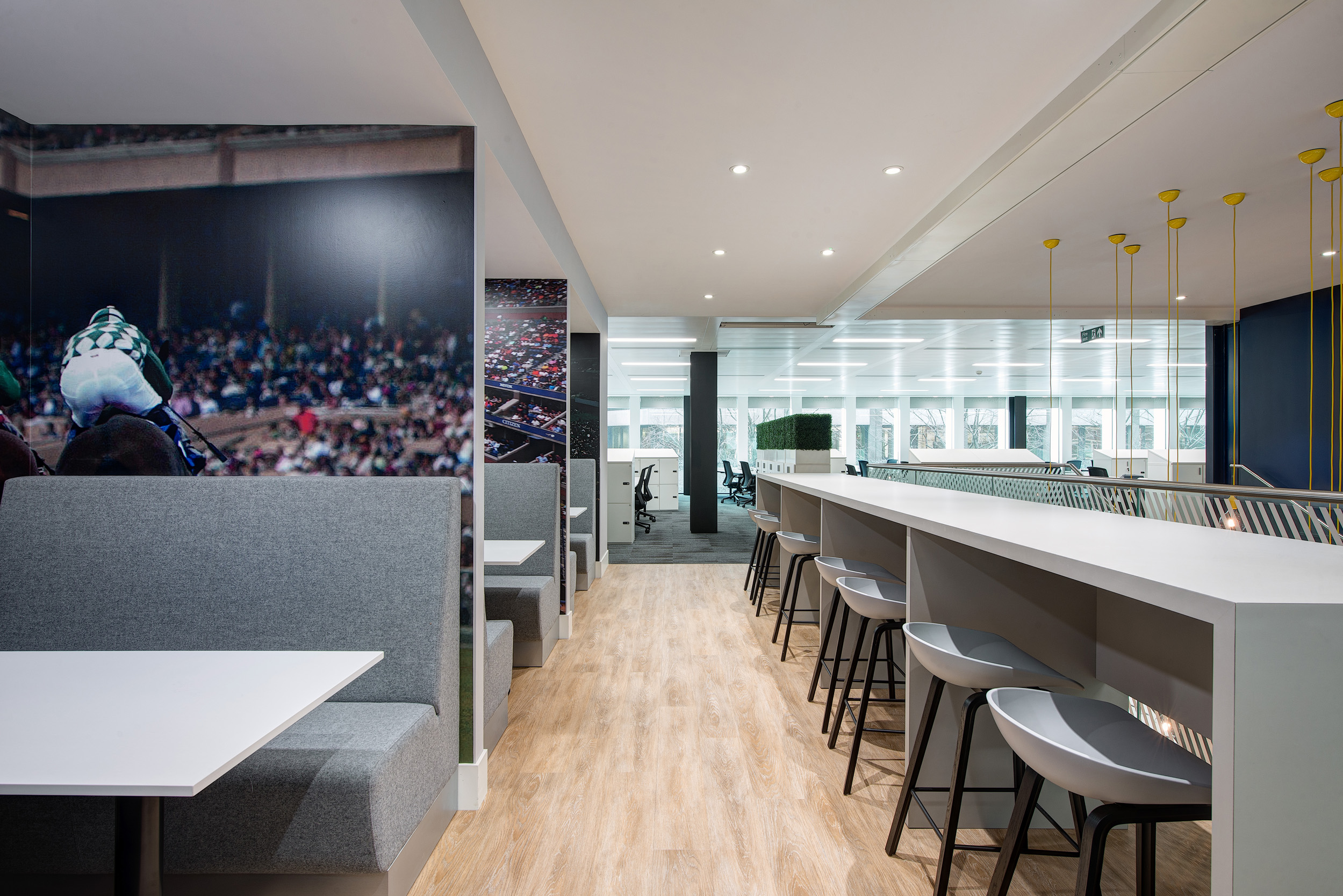 William Hill's open seating area, designed by Modus Workspace, with a sleek wooden staircase, spacious layout, and glass partitions provides a dynamic and flexible office design.
