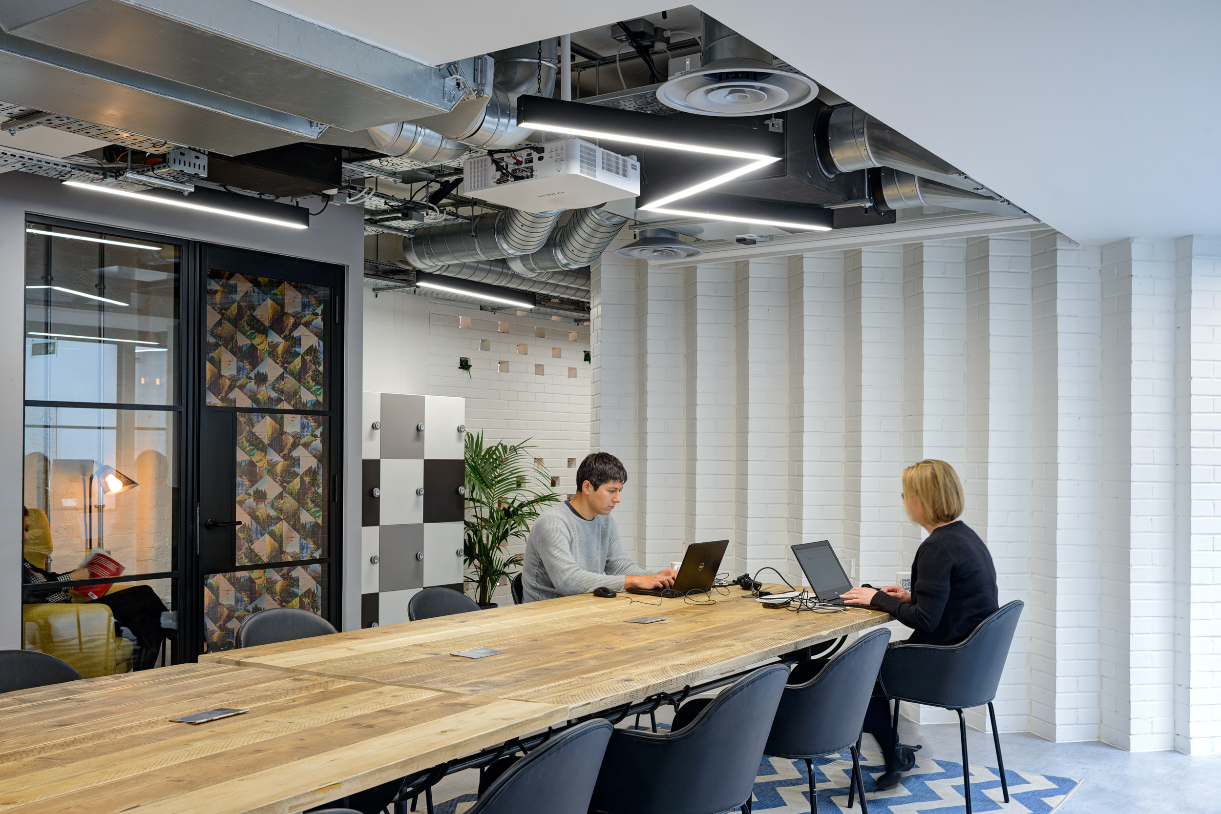 An open shared workspace with a long wooden table and industrial elements, providing flexibility for teams at Work.Life Bermondsey, designed by Modus Workspace.