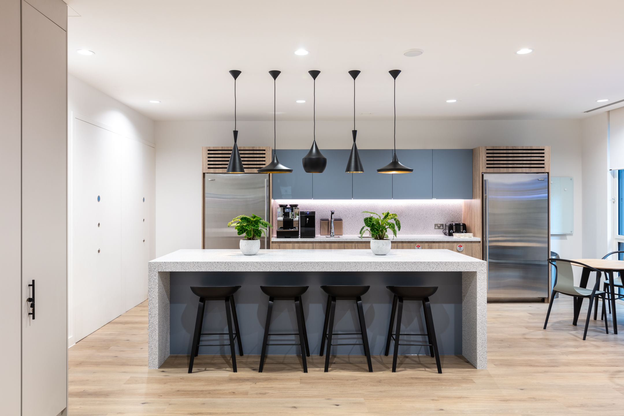Asset Management Firm Floor 3 teapoint featuring terrazzo speckled tiles and artistic black hanging lights.