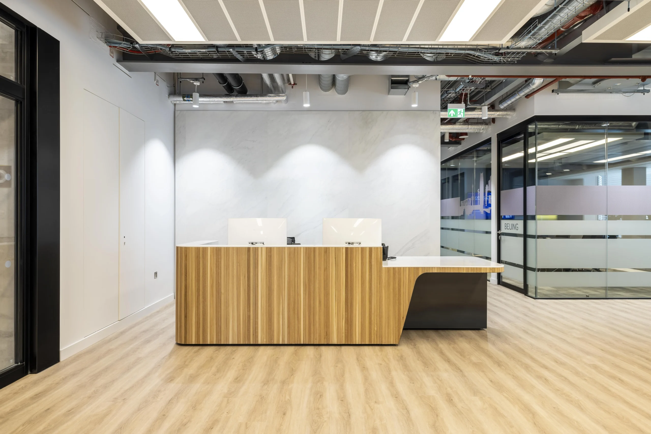 Investment Company reception area with fitted bespoke lighting and wood flooring, leaving a sleek and professional atmosphere.