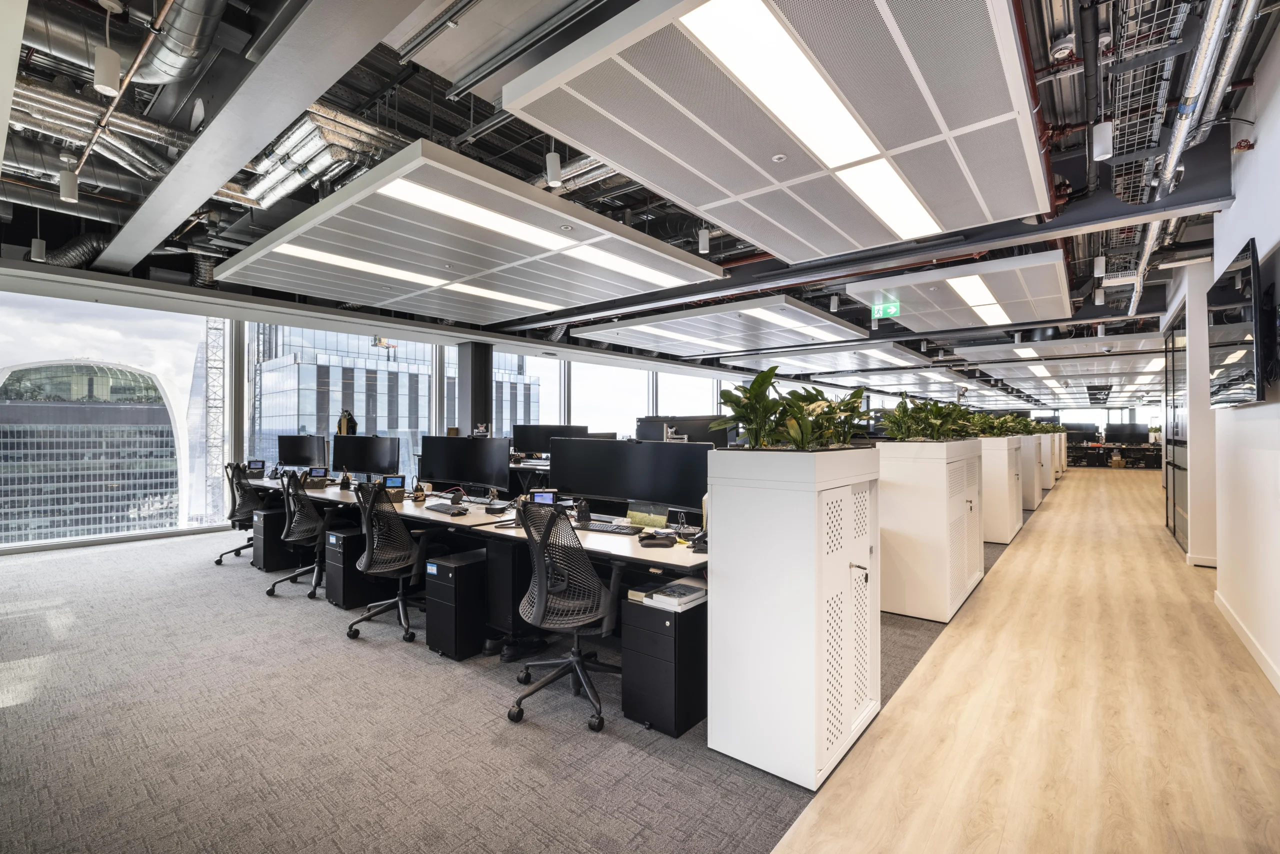 Investment Company open-plan workspace featuring biophilic plotted plants, large screens, desking and an immersive view of London's skyline