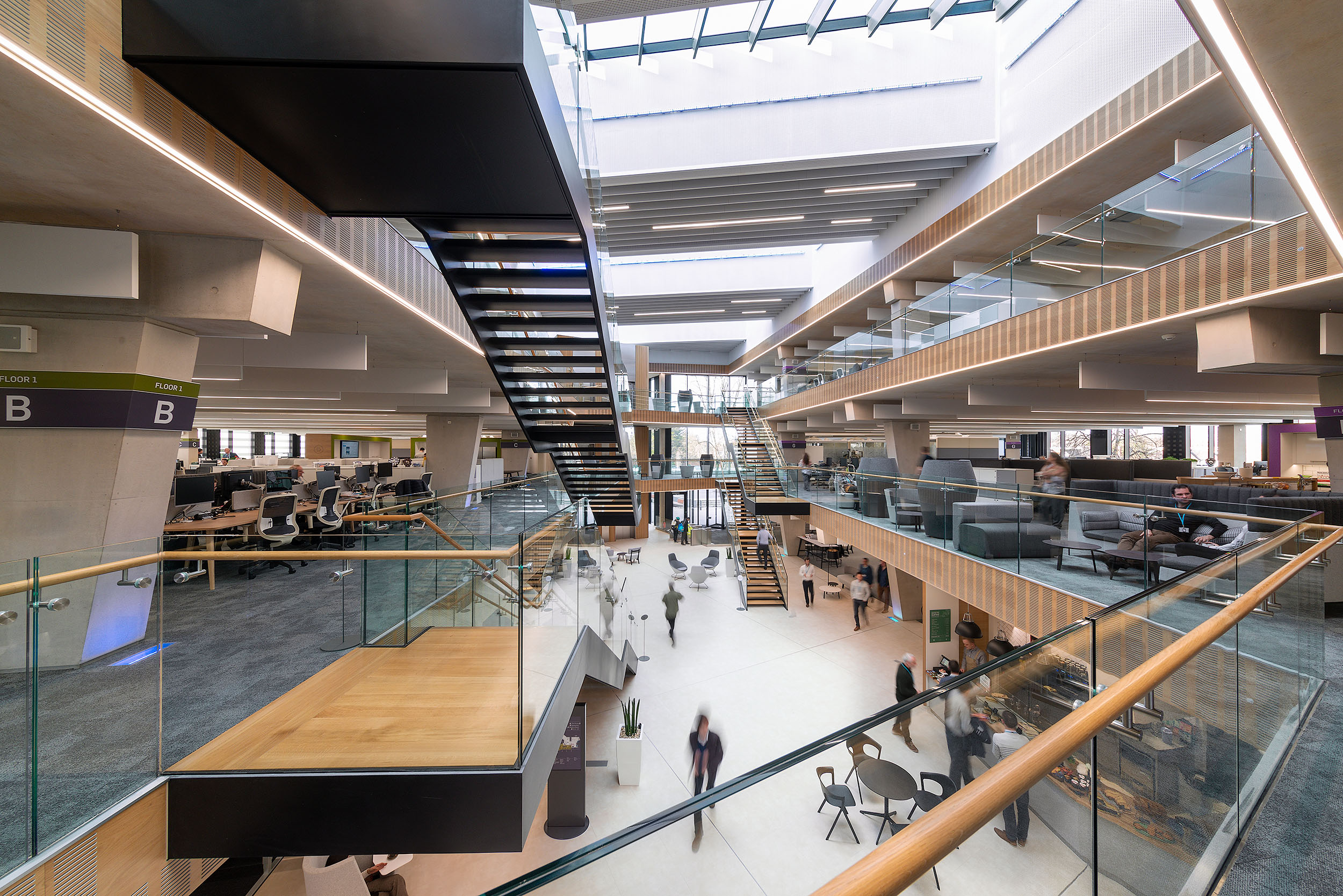 A spacious atrium at Atkins Woodcote Grove features a multi-level open-plan layout with glass railings and modern workstations on the upper floors.