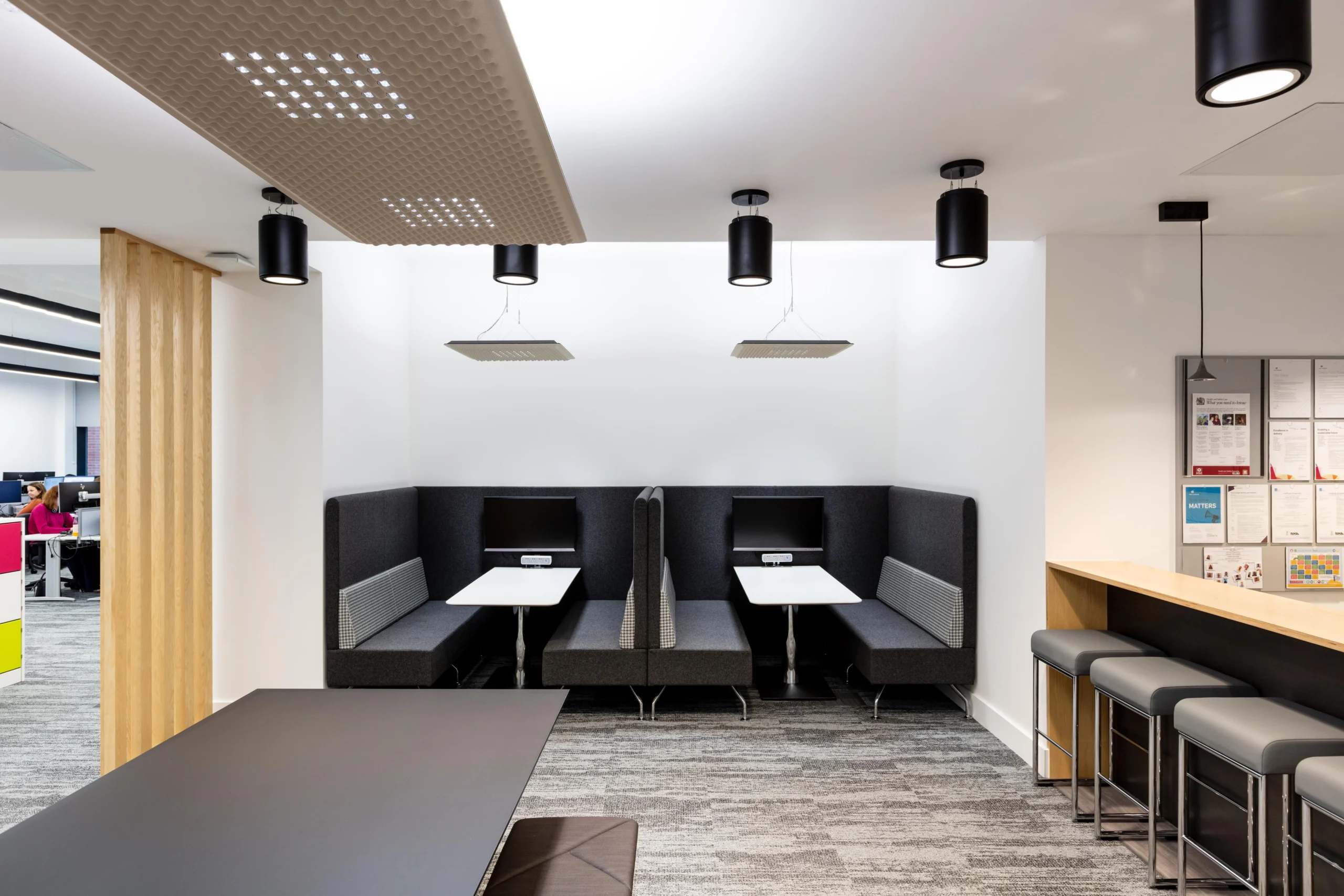 Informal booth seating at Atkins, designed for focused work or small meetings, paired with ceiling acoustic panels and comfortable cushions.