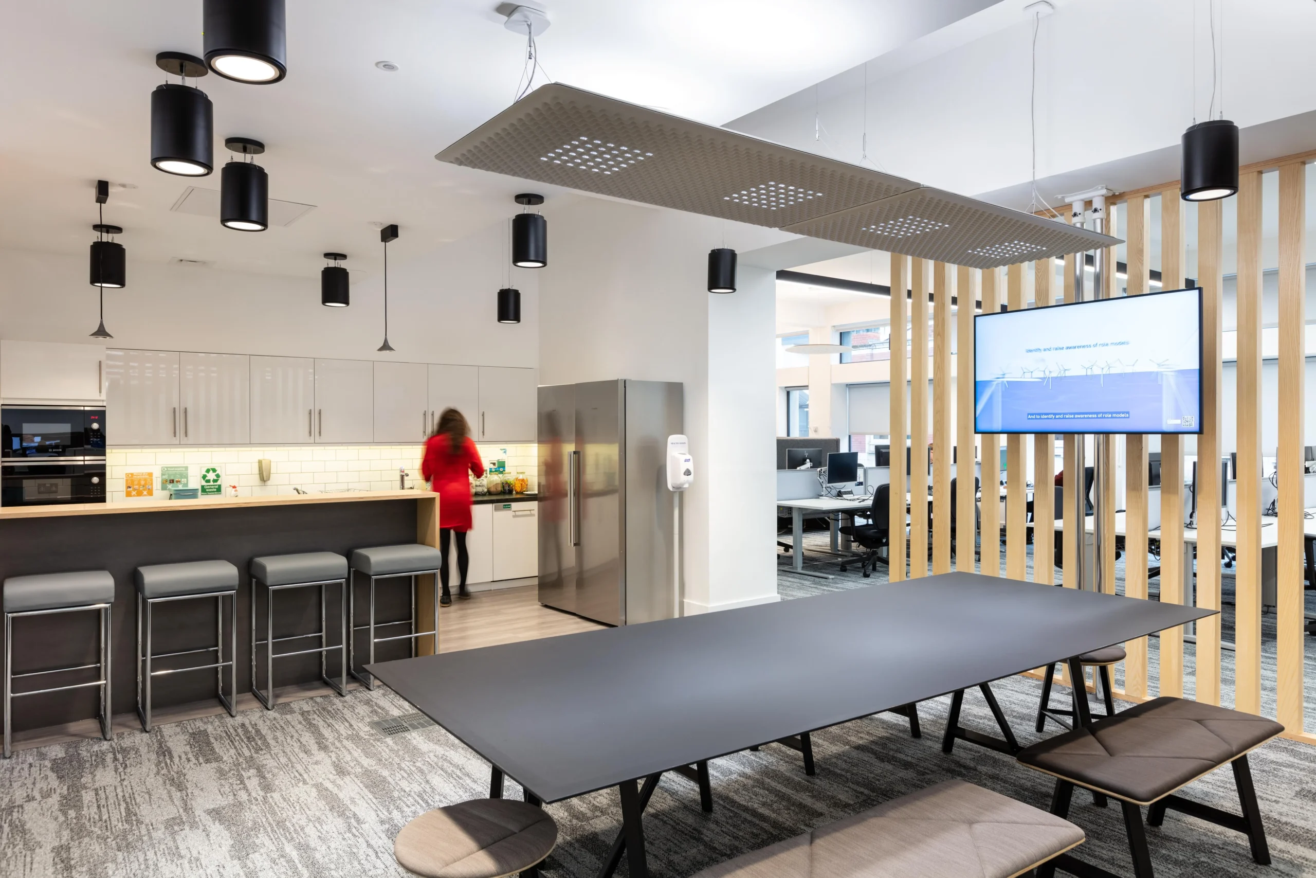 Teapoint and breakout area for Atkins, complete with a stainless steel fridge, bar seating, and modern lighting.