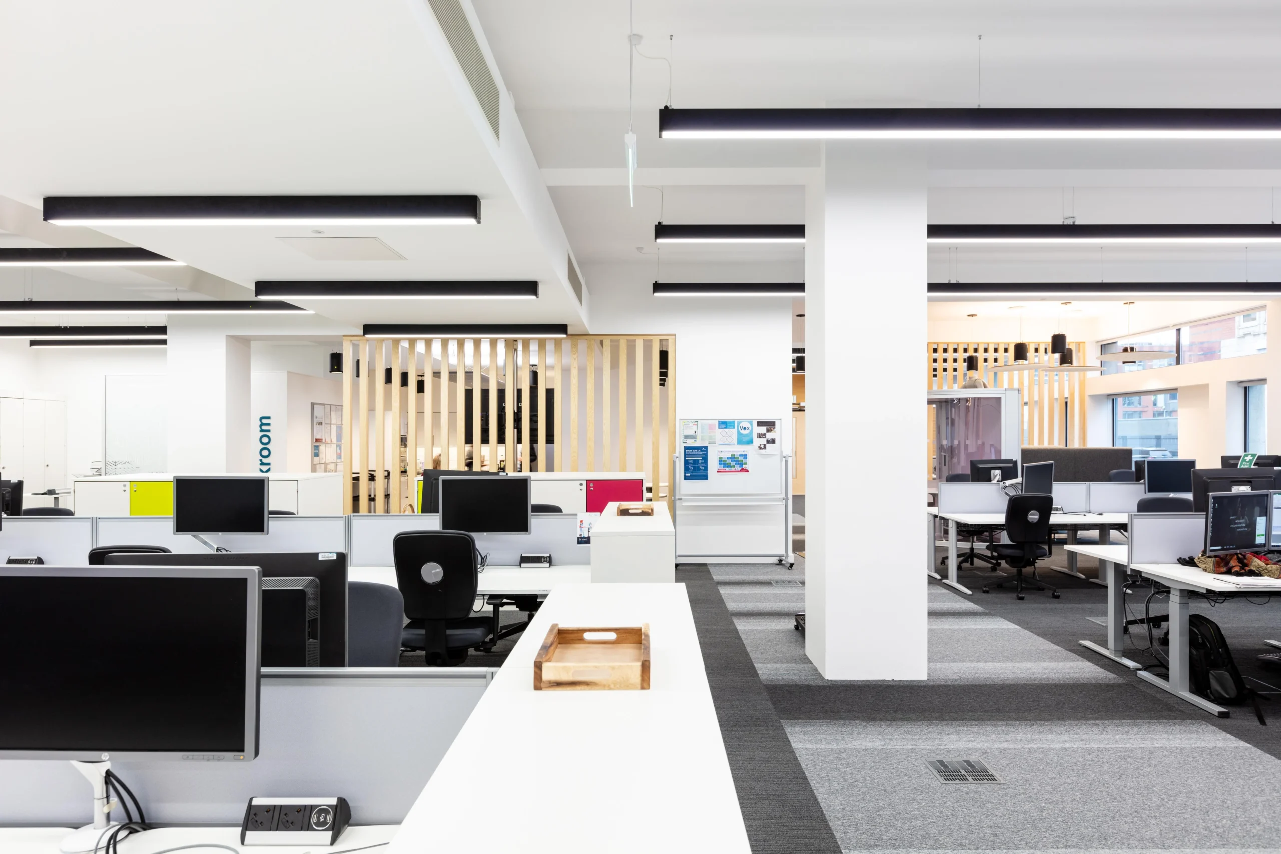 Spacious open-plan office at Atkins - The Exchange, featuring minimalist workstations, high ceilings, and natural light.