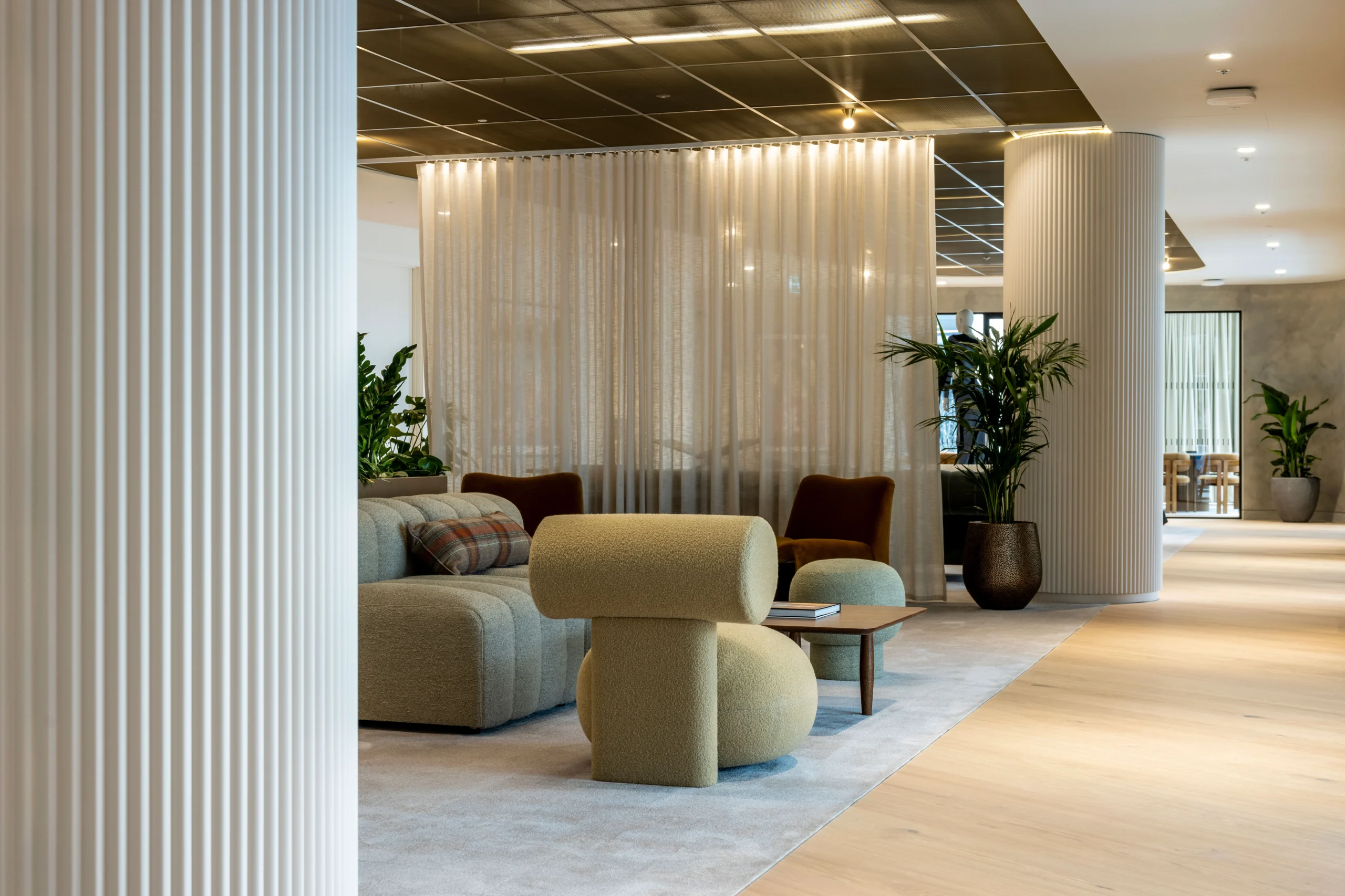 A seating corner at Authentic Brand Group, designed by Modus, with plush furniture and soft lighting, separated by a translucent curtain to create a semi-private atmosphere.