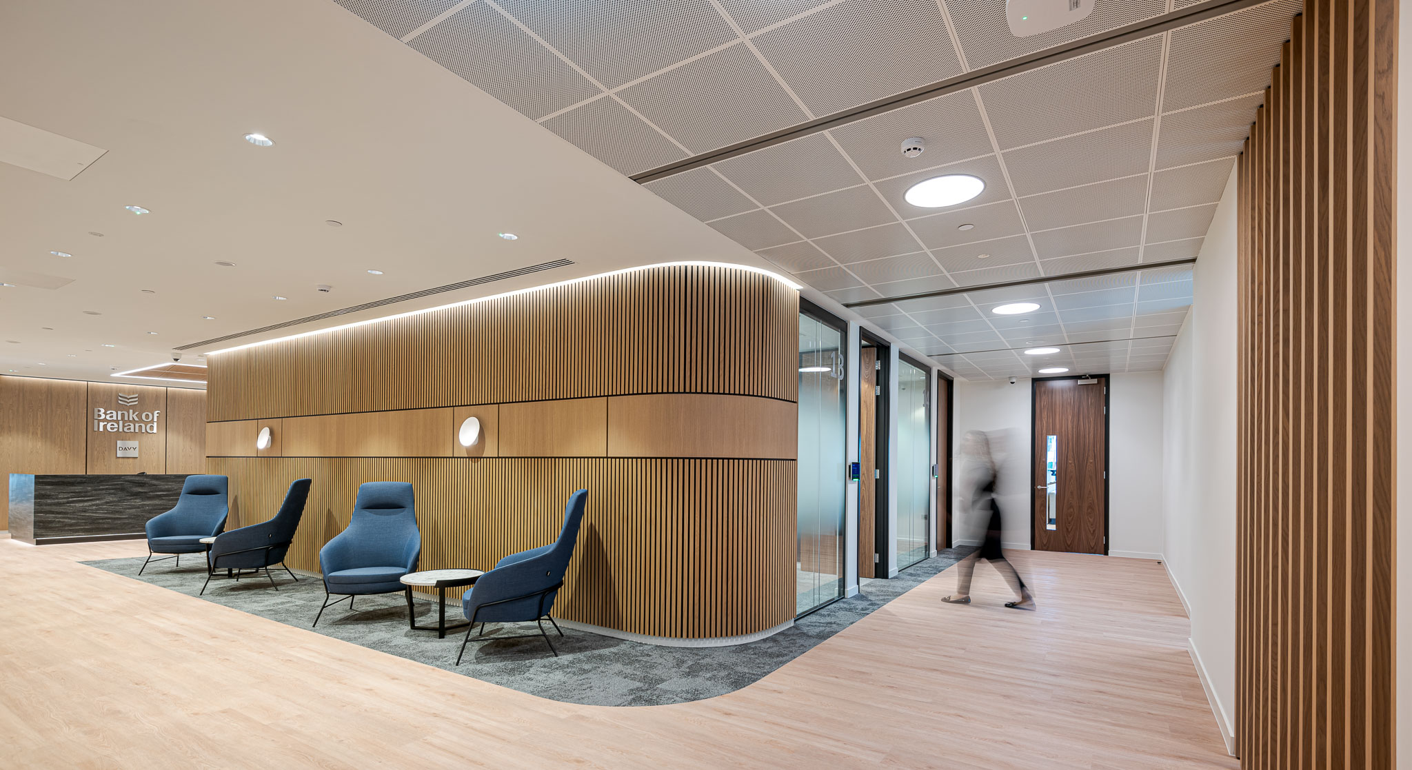 The hallway at Bank of Ireland, designed by Modus Workspace, features elegant wood finishes, bespoke signage and contemporary seating leading to meeting rooms.