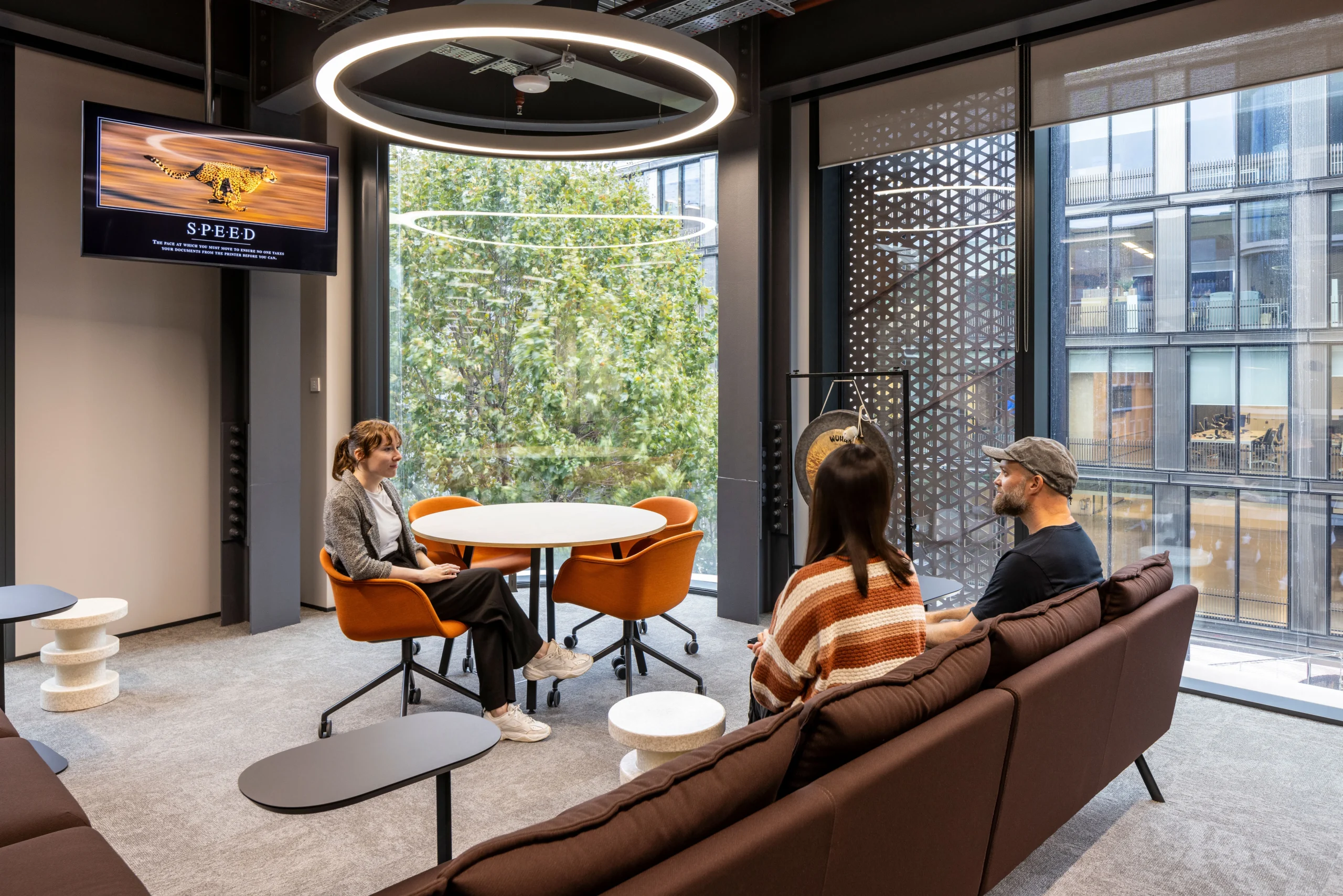 A cozy seating area in Bazaarvoice's London office, designed by Modus Workspace, where employees have a relaxed discussion. The space is welcoming, with thoughtful design and comfortable furniture.