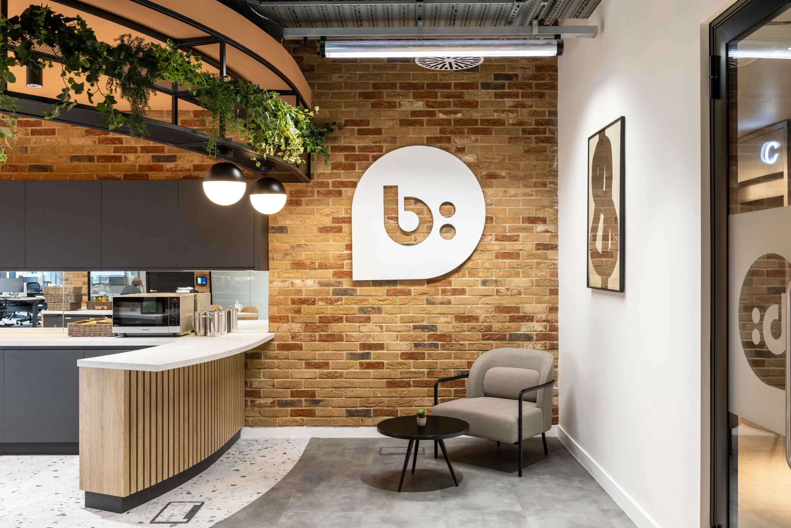The reception area at Bazaarvoice's London office, designed by Modus Workspace, blending modern branding with exposed brick. The space offers a professional yet inviting atmosphere.