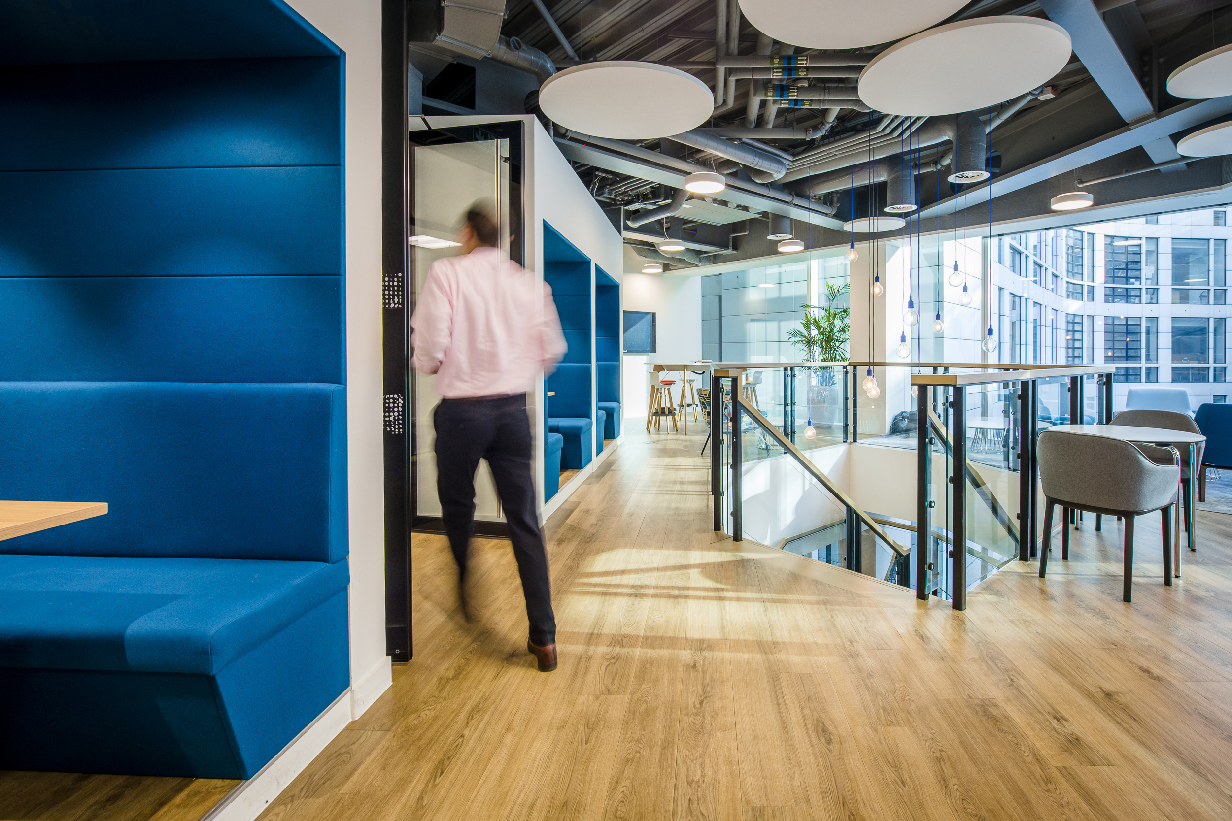 CRA private booths Interior view of Charles River Associates' office designed by Modus, showcasing blue seating booths and modern lighting.