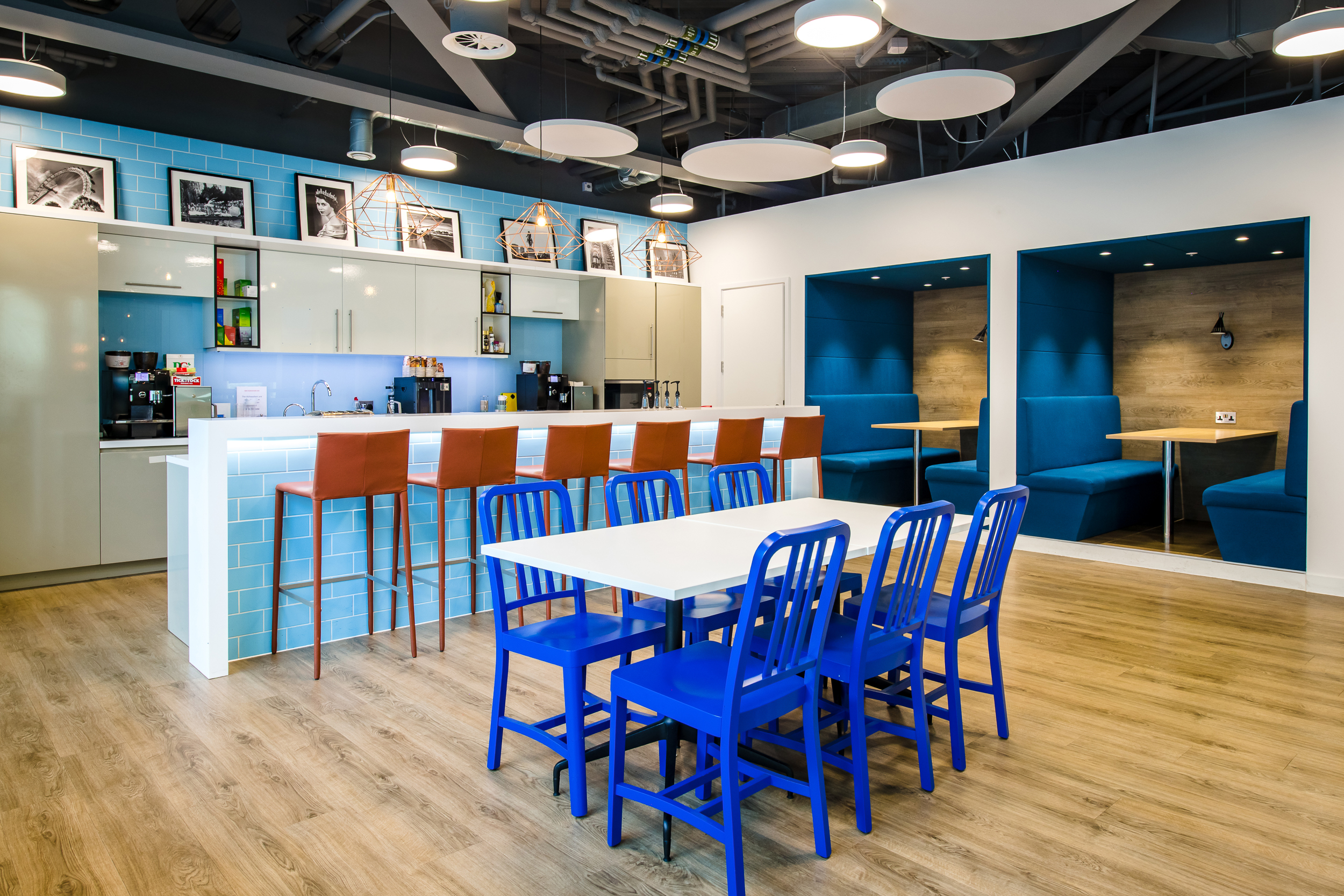 CRA teapoint at Charles River Associates with blue chairs, high stools, and a vibrant colour scheme, designed by Modus Workspace.