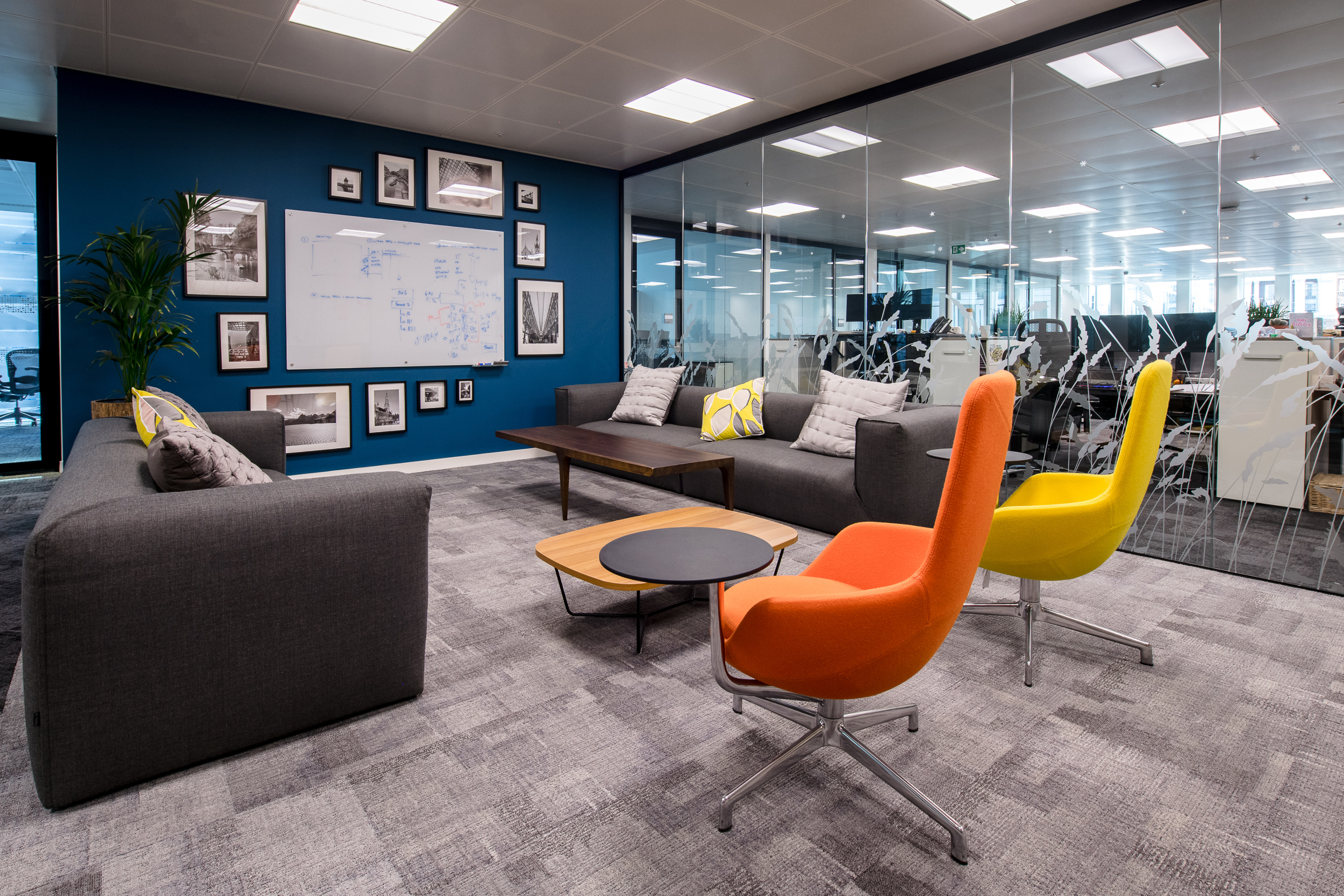 CRA Comfortable office lounge area at Charles River Associates with grey sofas and vibrant decor, designed by Modus.