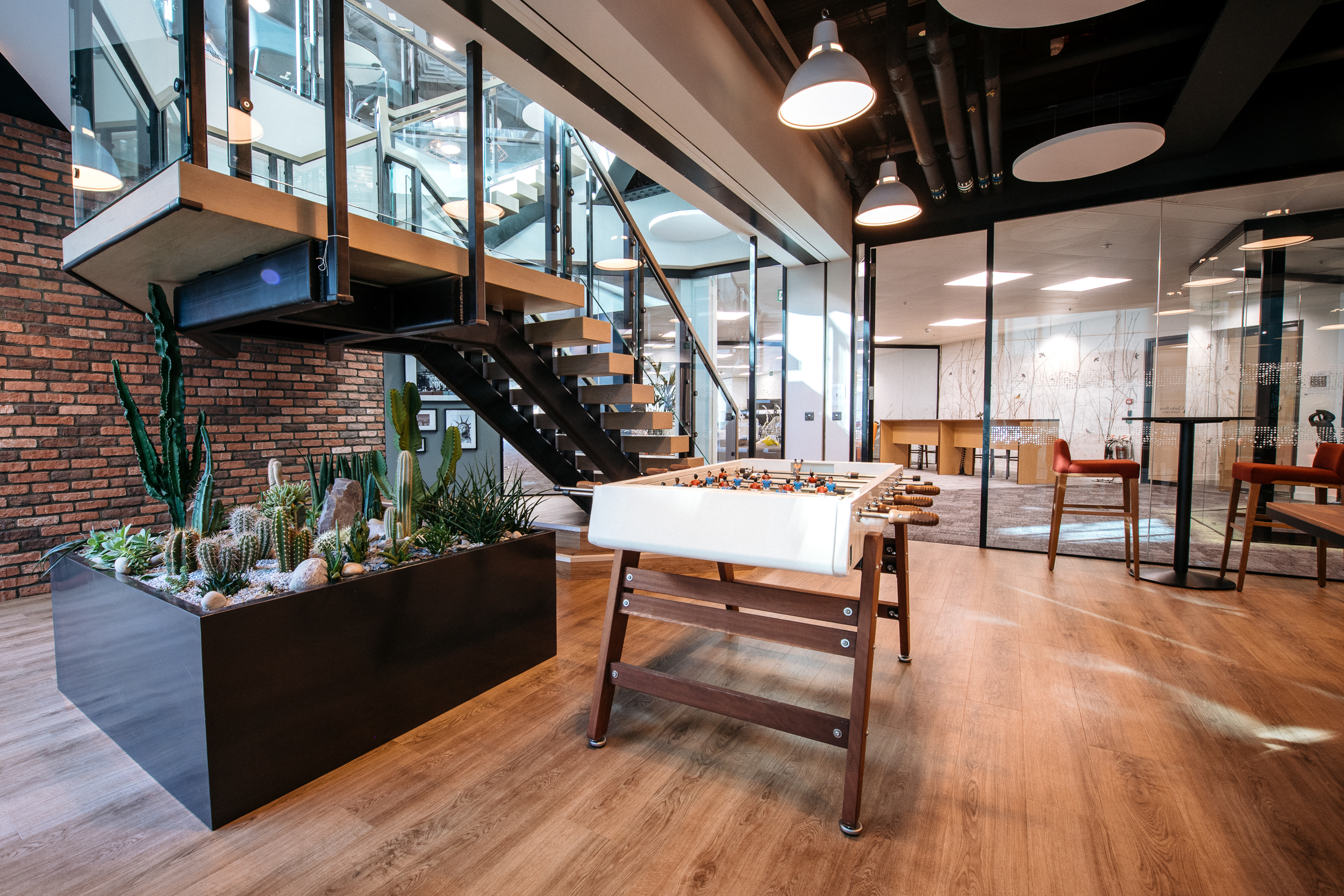 CRA Open Workspace central staircase with glass railings and a cacti display in the Charles River Associates office designed by Modus Workspace.