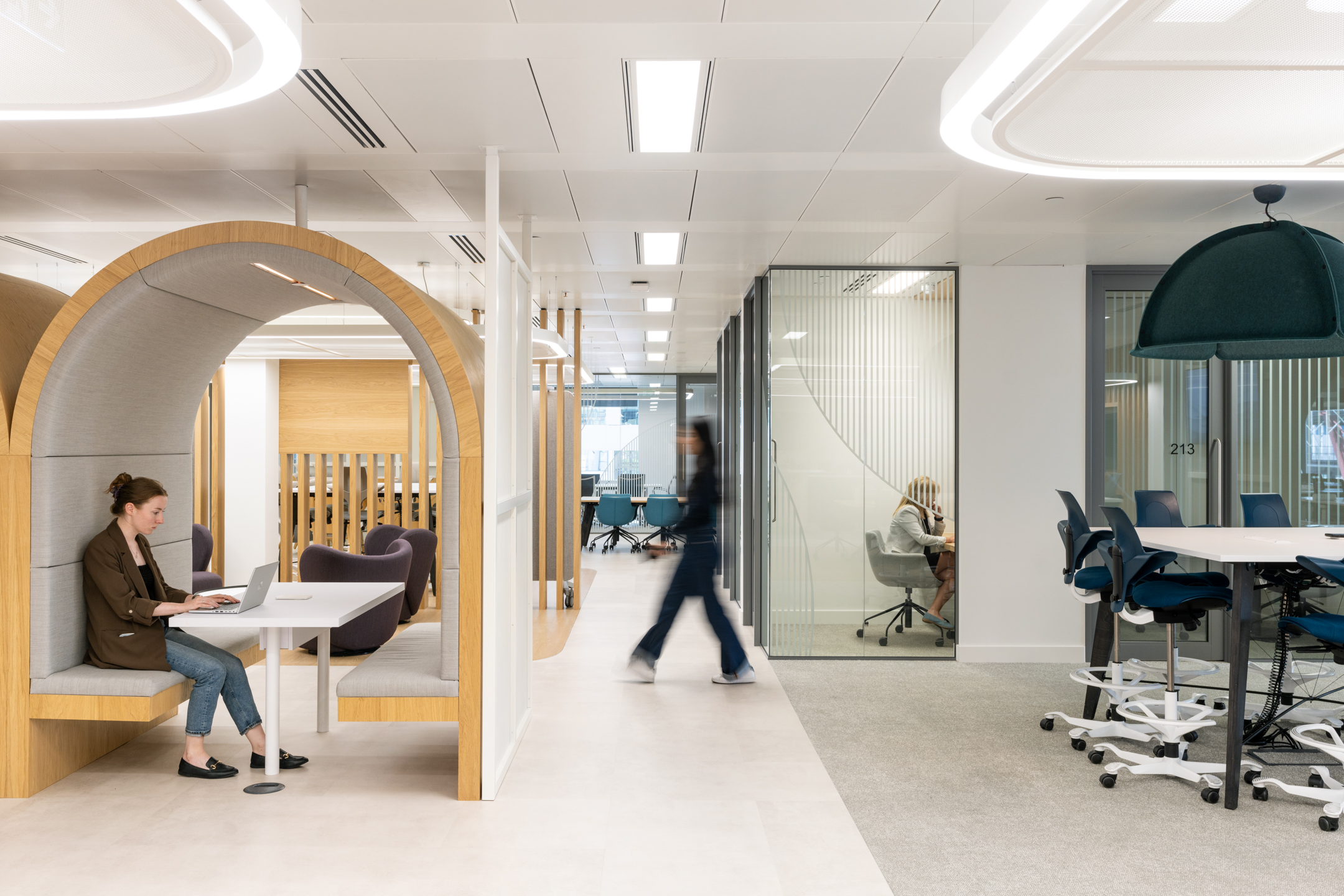 DXC Technology's private working nook, features a curved wooden frame, cushioned seats, and individual tables, with open office areas in the background.