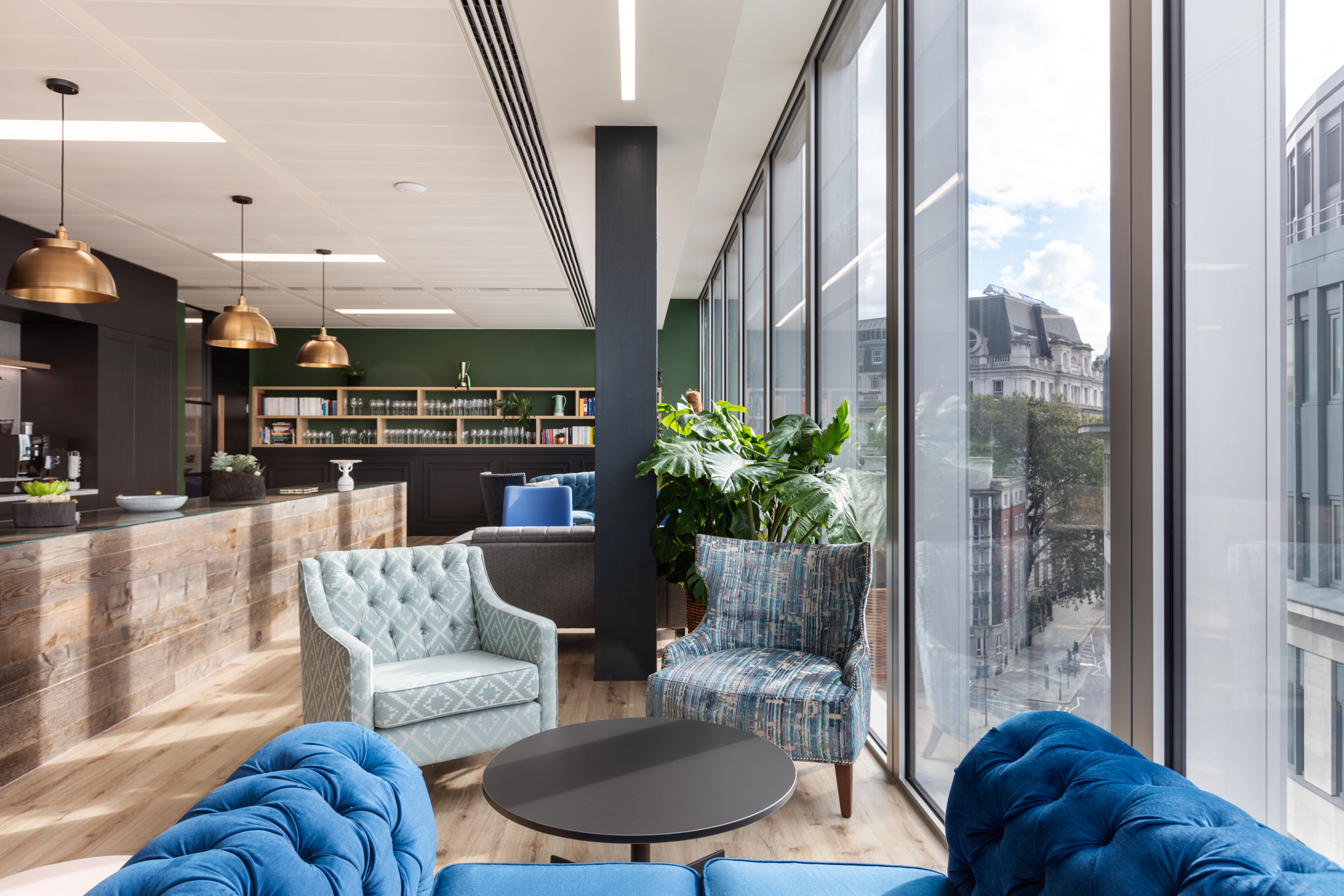 Fincap's teapoint seating area with plush, brightly coloured seating, large windows, and indoor plants.