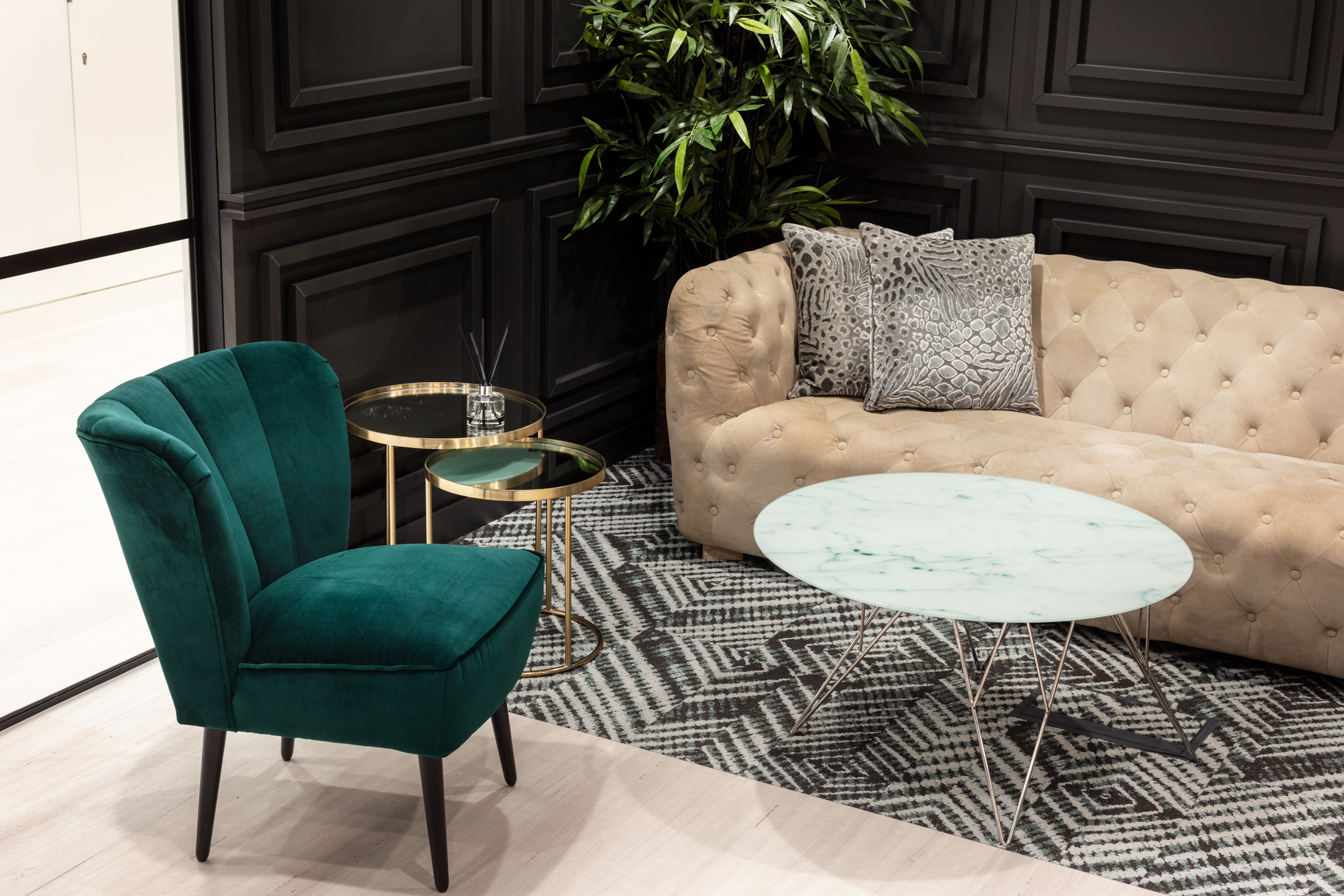 Fincap's close-up reception seating area, including a green velvet chair and a round marble table, with textured patterns and rich materials enhancing the luxurious feel.