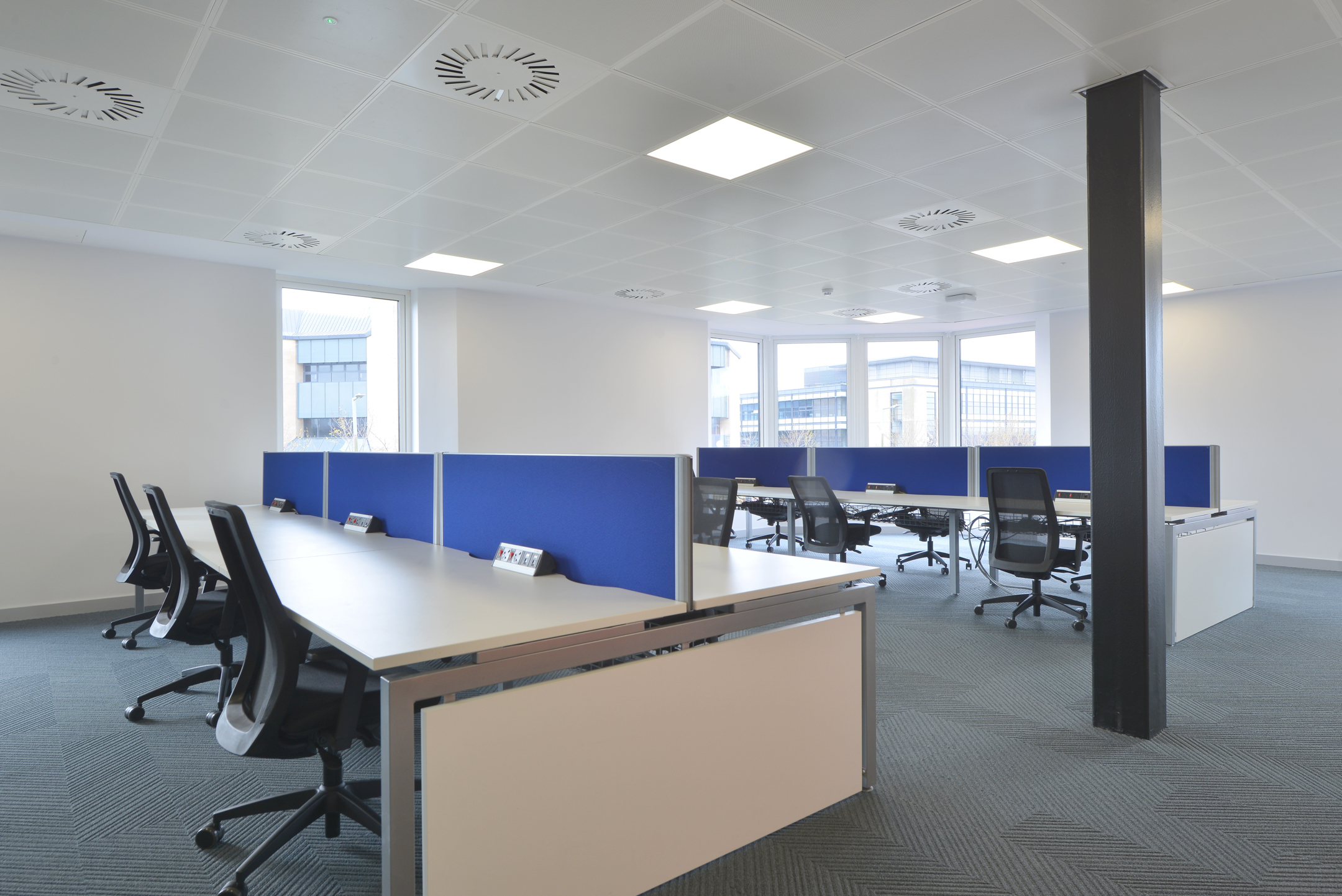 Bright workspace with individual desks and vibrant blue dividers at Fujitsu Services Edinburgh. Designed by Modus Workspace to promote focused work in a comfortable setting.