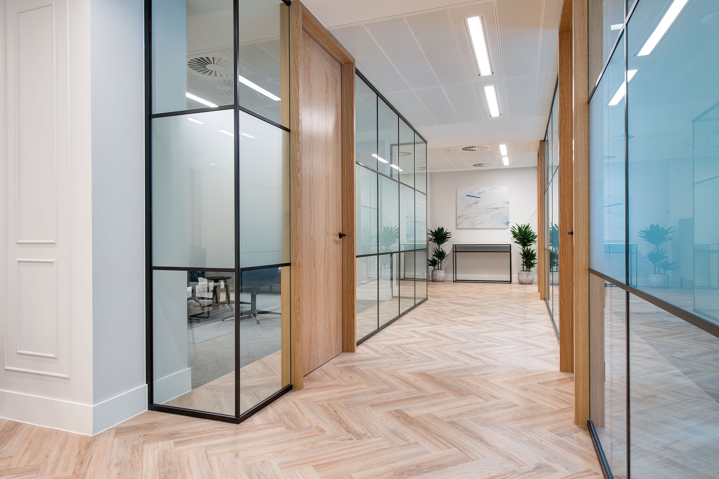 Bright and modern hallway in Guinness Asset Management's office designed by Modus Workspace, showcasing glass partitions and wooden accents for a sleek and open feel.