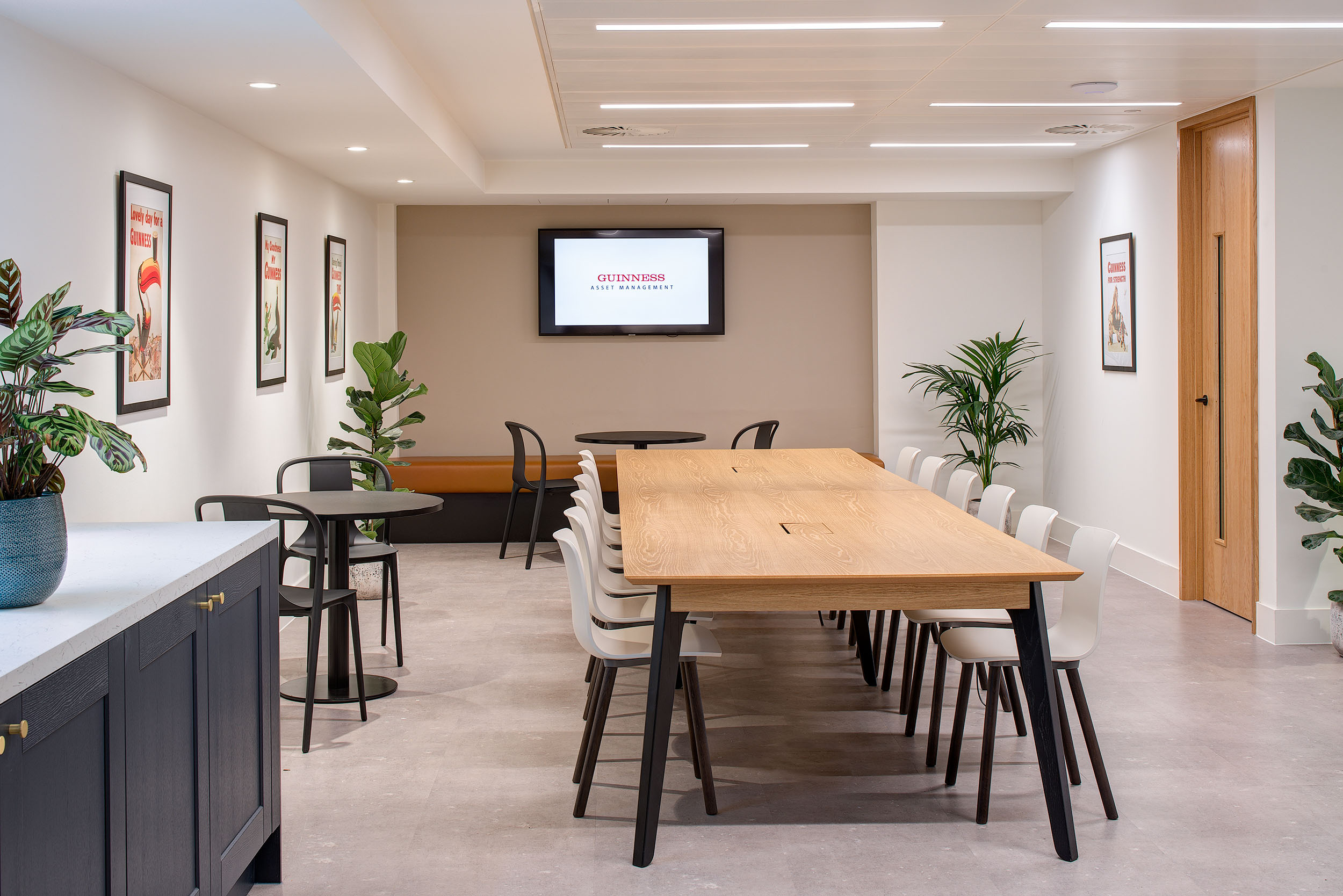 A sleek dining space in the Guinness Asset Management office designed by Modus Workspace, featuring contemporary furniture and framed wall art for a sophisticated touch.