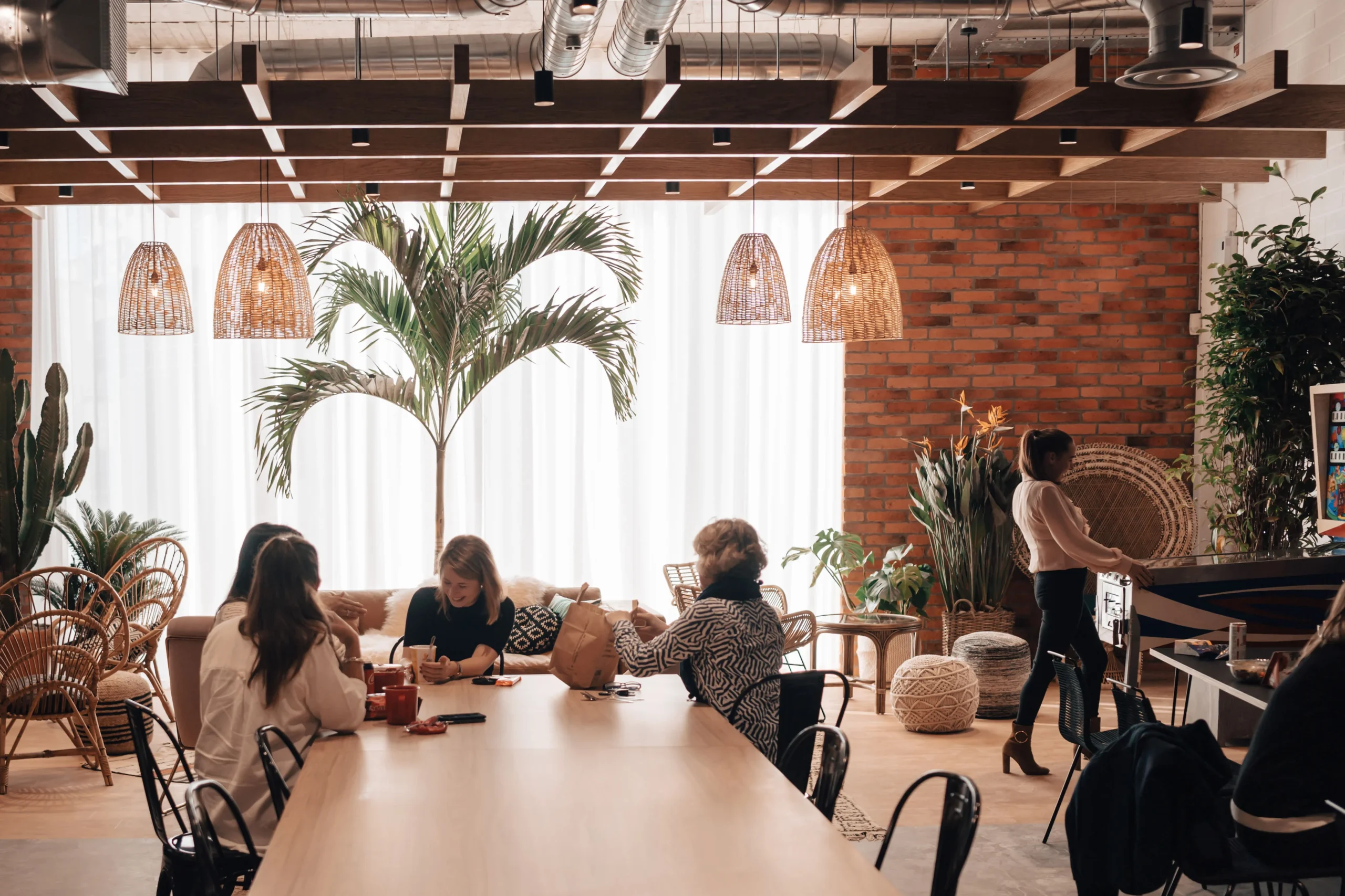 SLG's workspace features a warm, inviting breakout area with woven light fixtures, plants, and a collaborative atmosphere designed by Modus.
