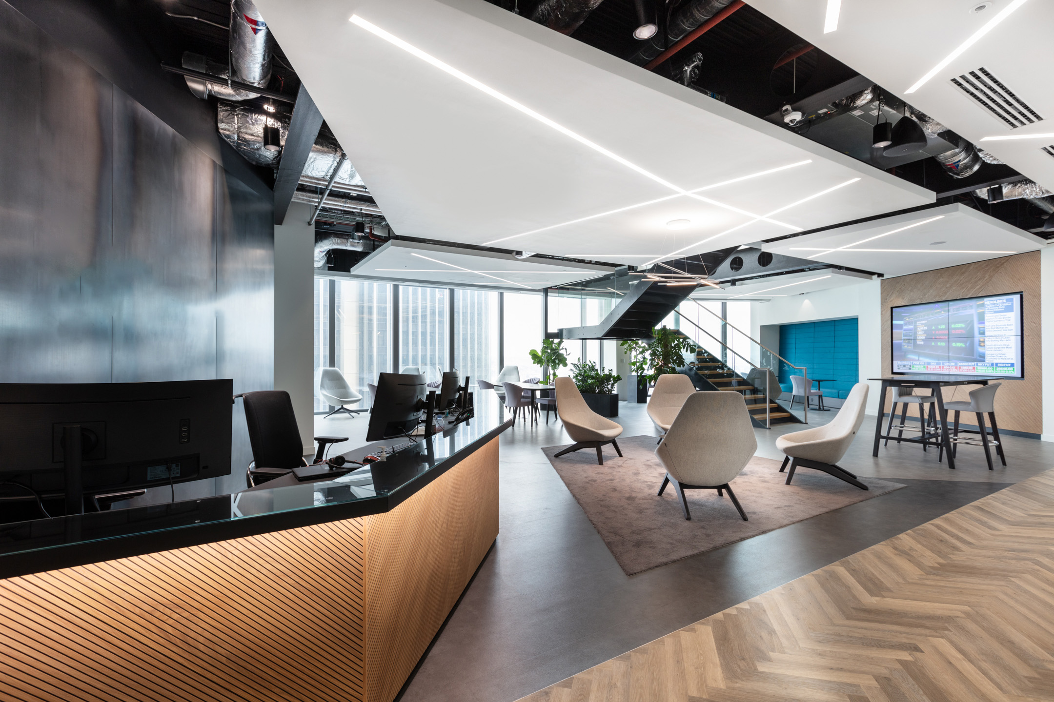 The reception area at the Insurance and Risk Management Firm in Bishopsgate features a sleek wood-accented desk, minimalist seating, and large windows offering city views.