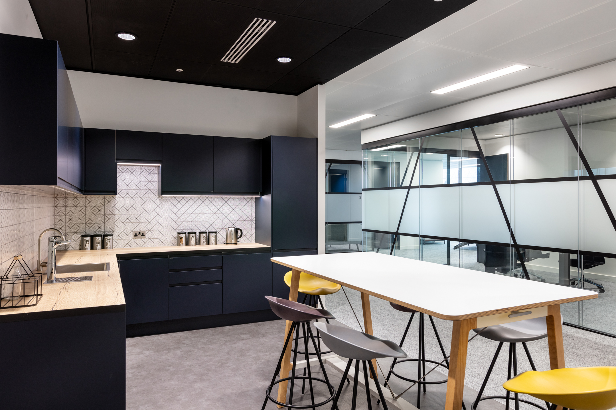 A navy teapoint with sleek black cabinets and a table, located in the Insurance and Risk Management Firm’s office in Bishopsgate.