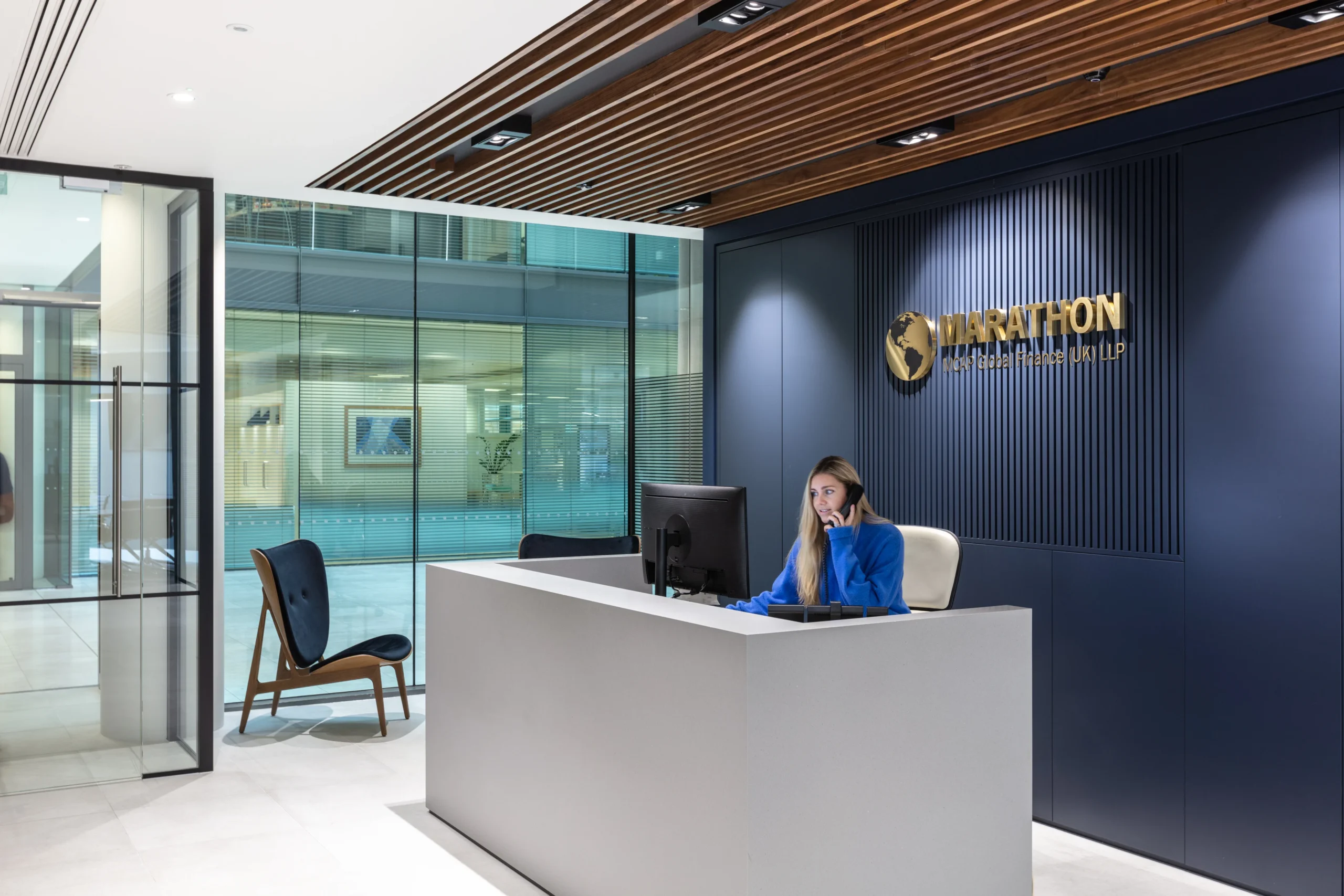 MCAP reception designed by Modus features wooden ceiling panels and a modern reception desk. The space combines elements of wood and sleek design for a welcoming entrance.