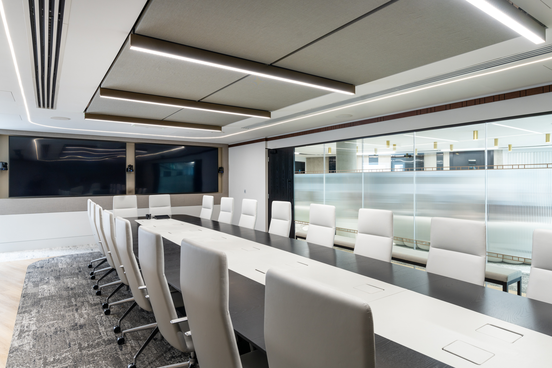 Spacious boardroom in Seplat Energy office with sleek chairs, large screen, and frosted glazing partitions.