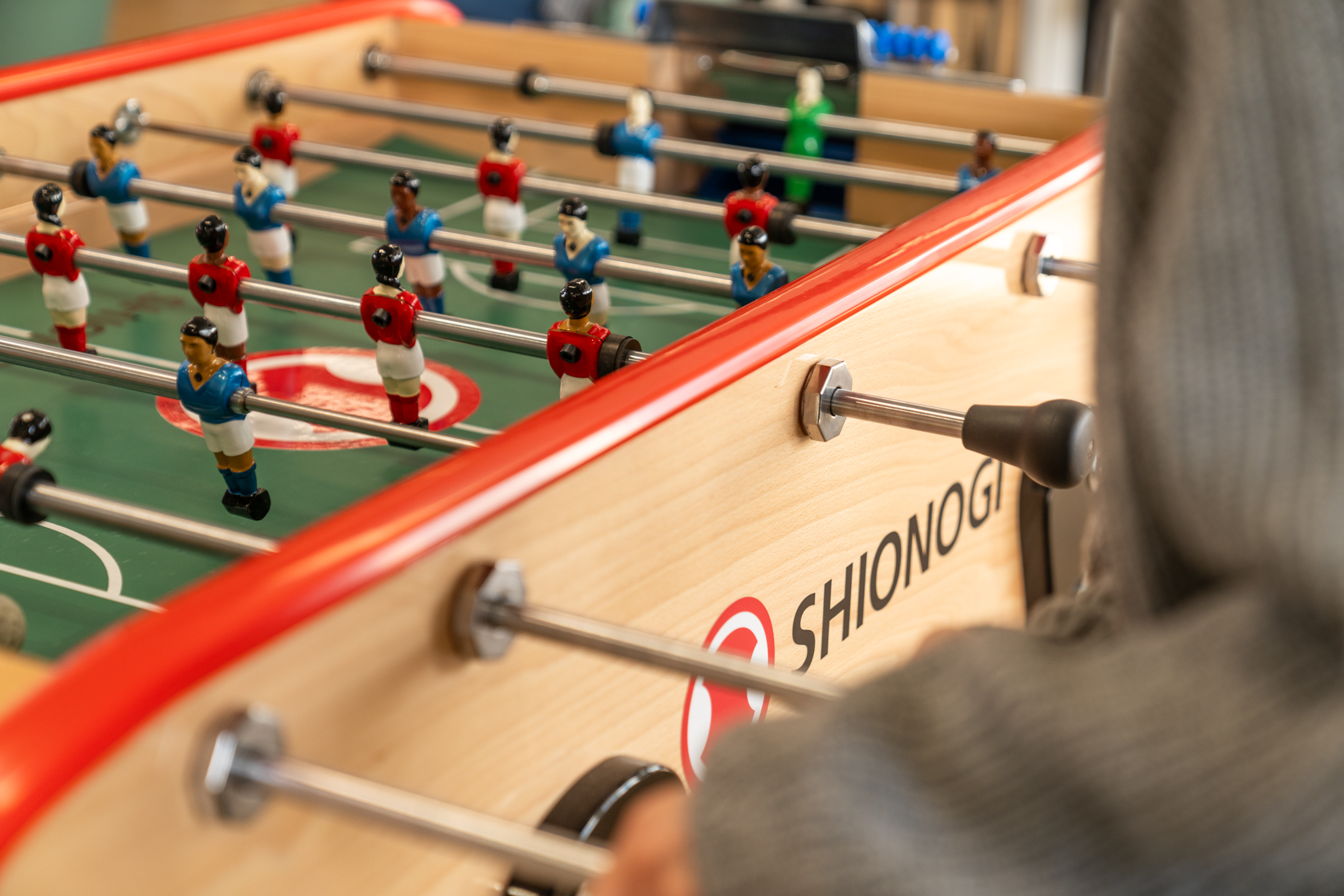 Shionogi branded foosball table with women characters in football Shionogi Kit red and blue players.
