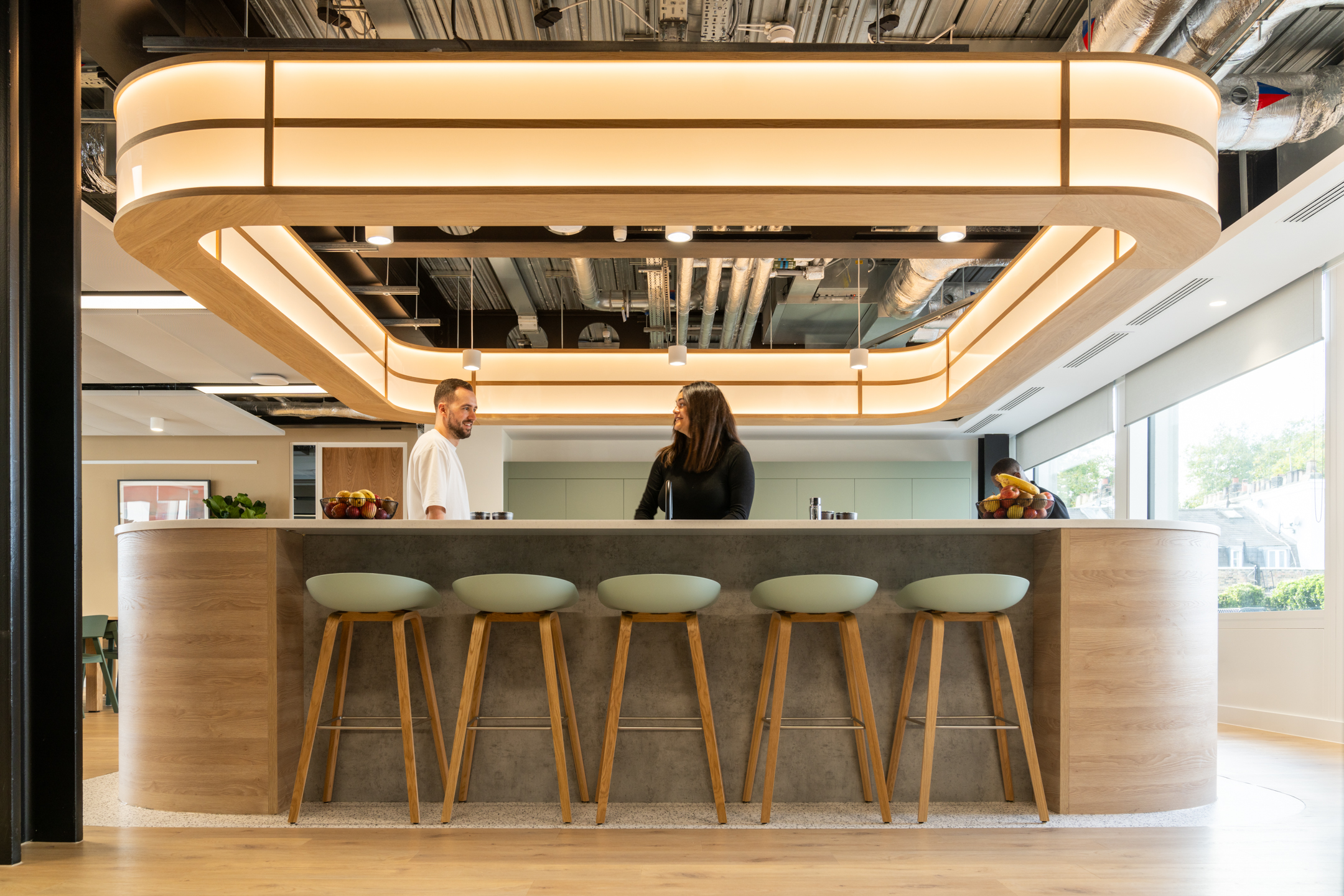 Shionogi teapoint with a curved bar, stools, glowing light fixture, and exposed ceiling.