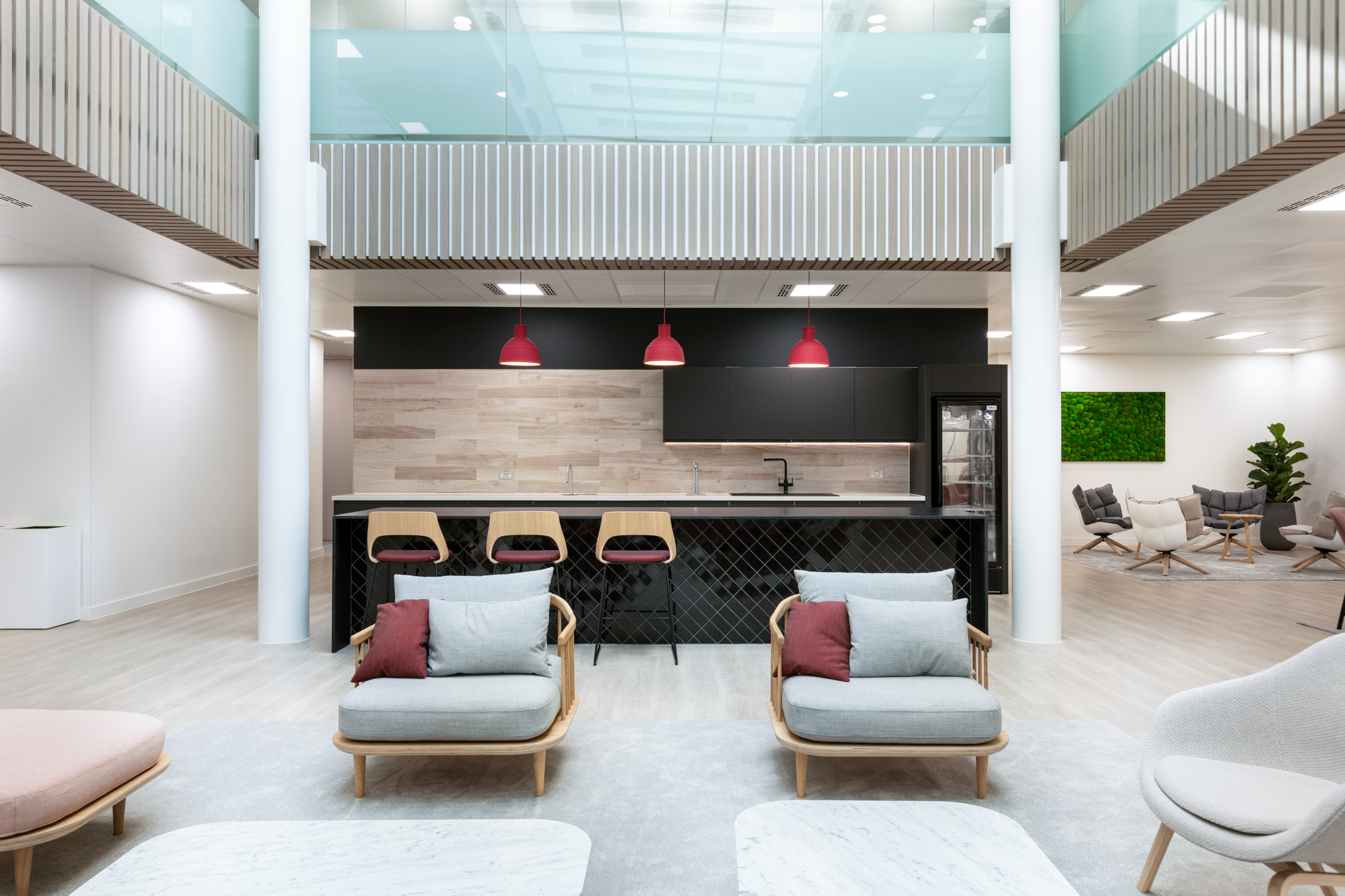 The open-plan lounge at Fujitsu Services Marylebone, complete with comfortable seating and a black tiled teapoint. A modern office design by Modus Workspace.