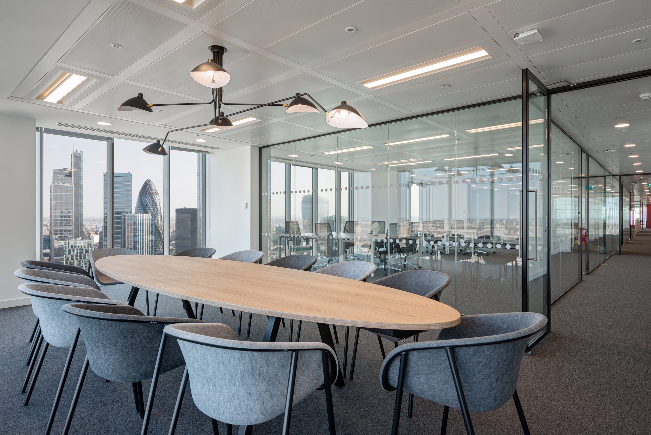Meeting room in Primalbase's office designed by Modus Workspace, featuring a large table, modern chairs, and panoramic views of London’s financial district.