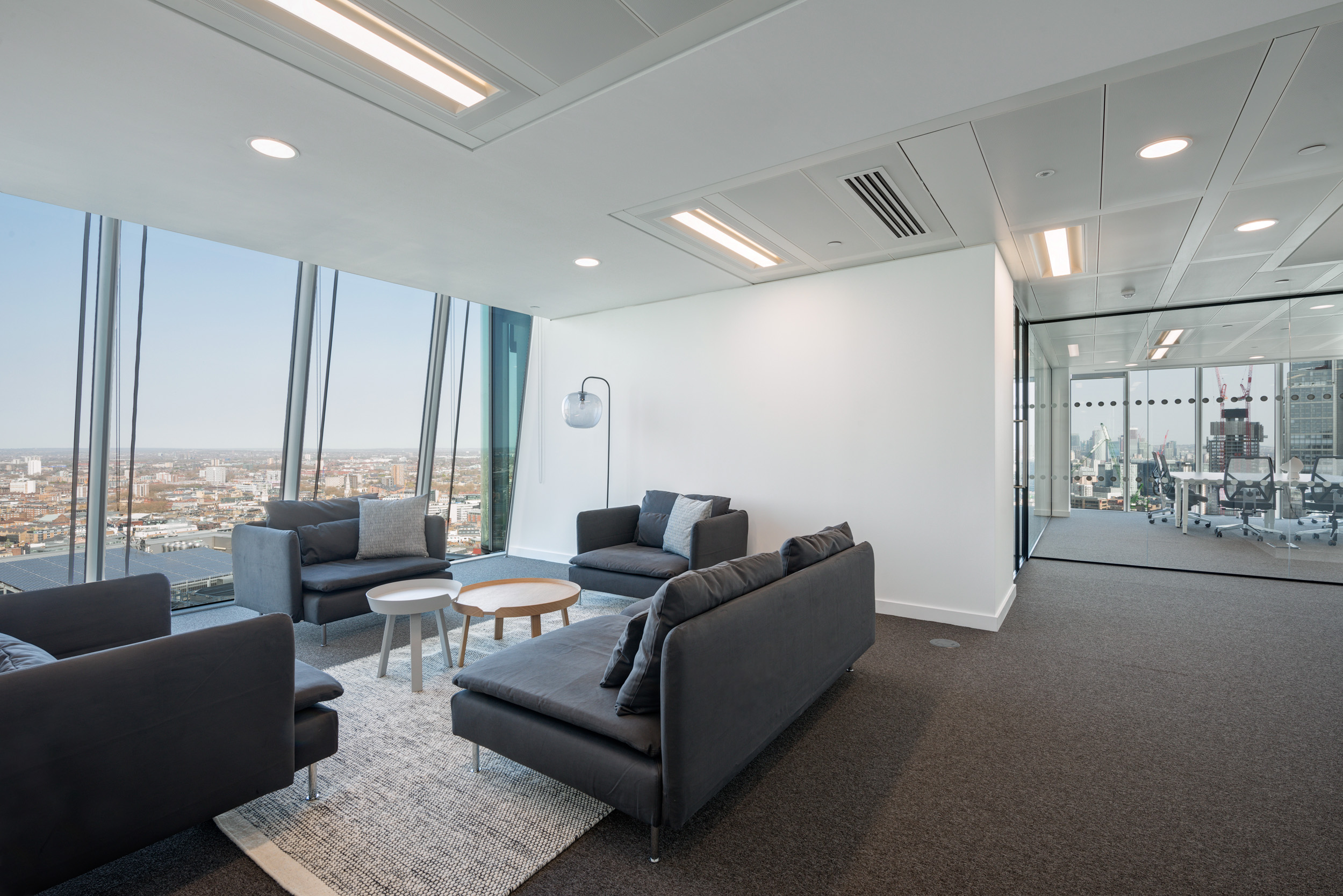 Seating area in Primalbase's office designed by Modus Workspace, with comfortable sofas, round tables, and expansive views, offering a relaxed environment for informal meetings.