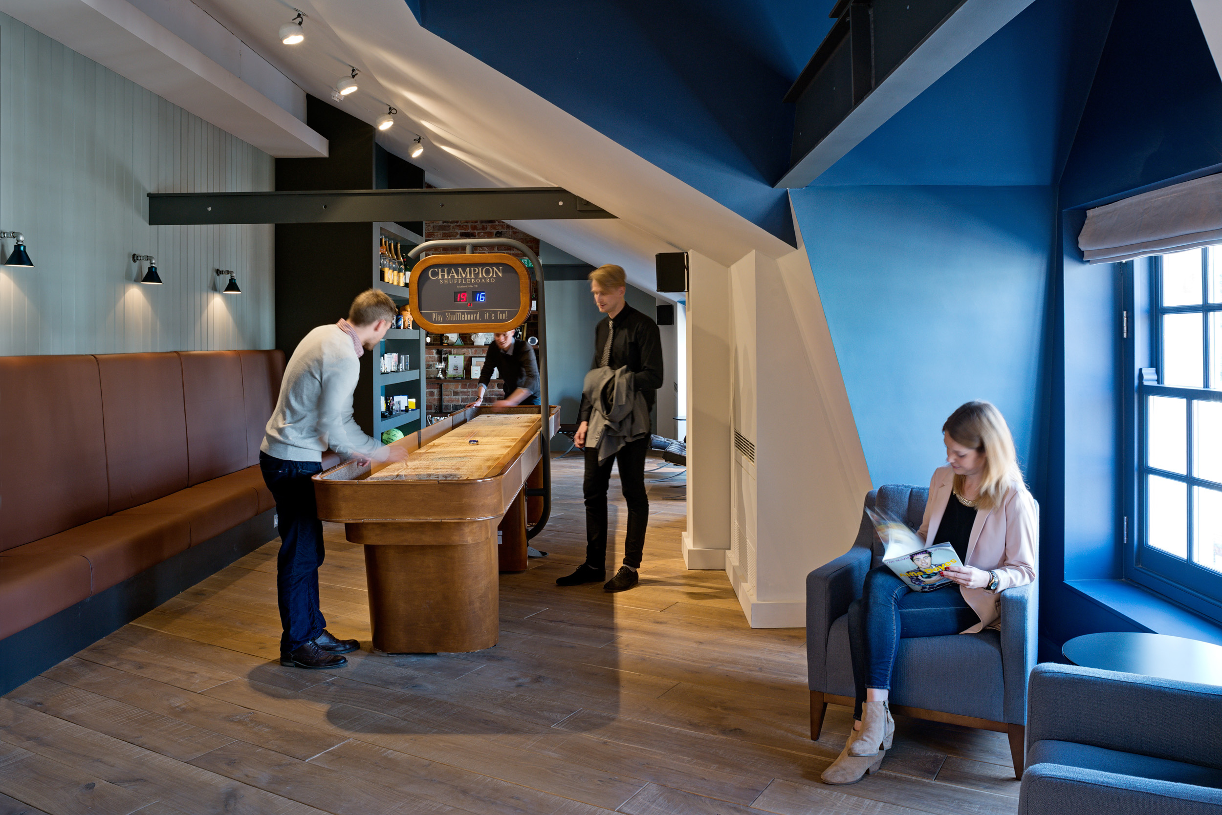 Gaming area at Private Equity Firm with a blue feature wall and brown, leather seating.