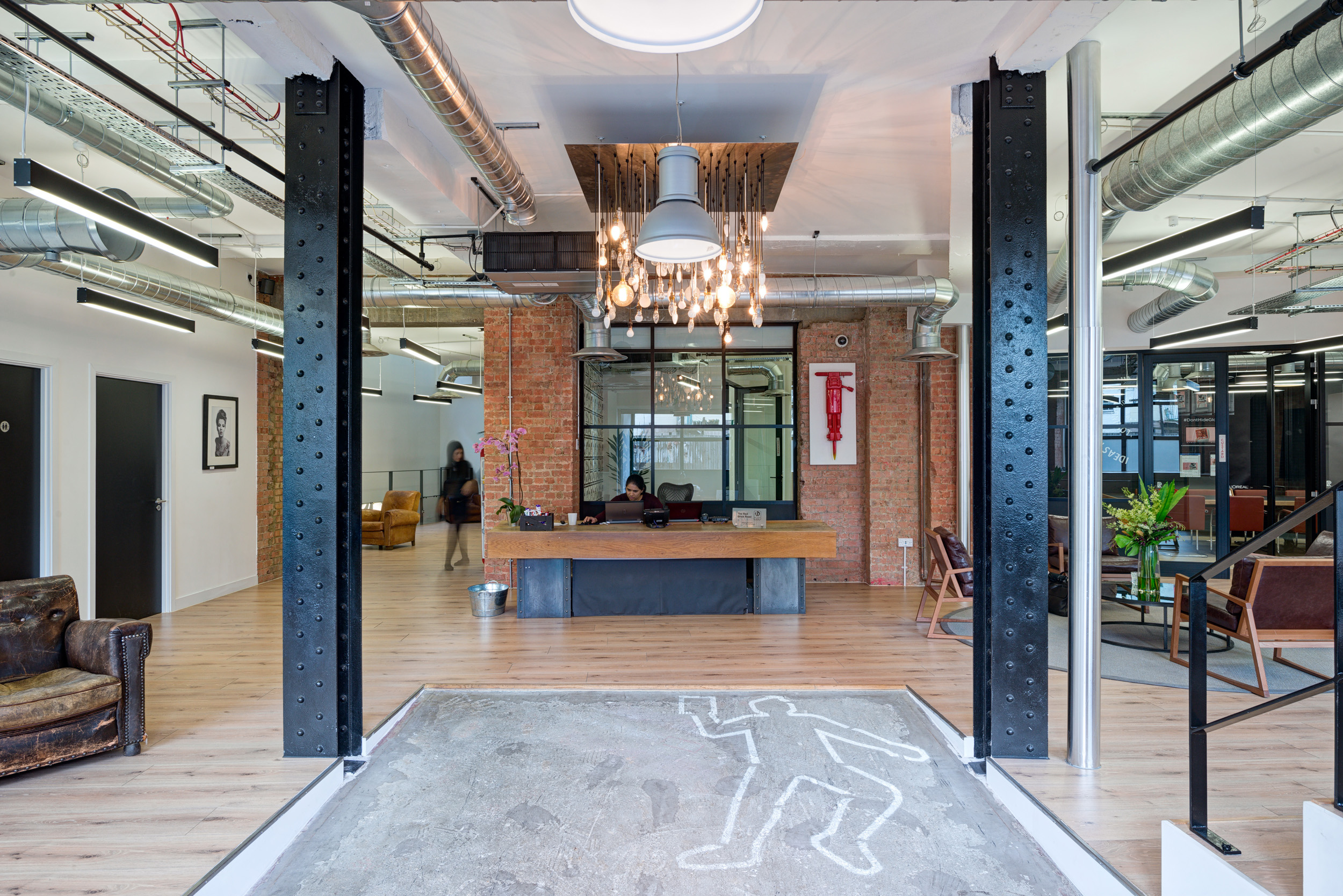 The reception area of the Red Brick Road office has exposed brick walls, industrial metal beams, and a unique light fixture.
