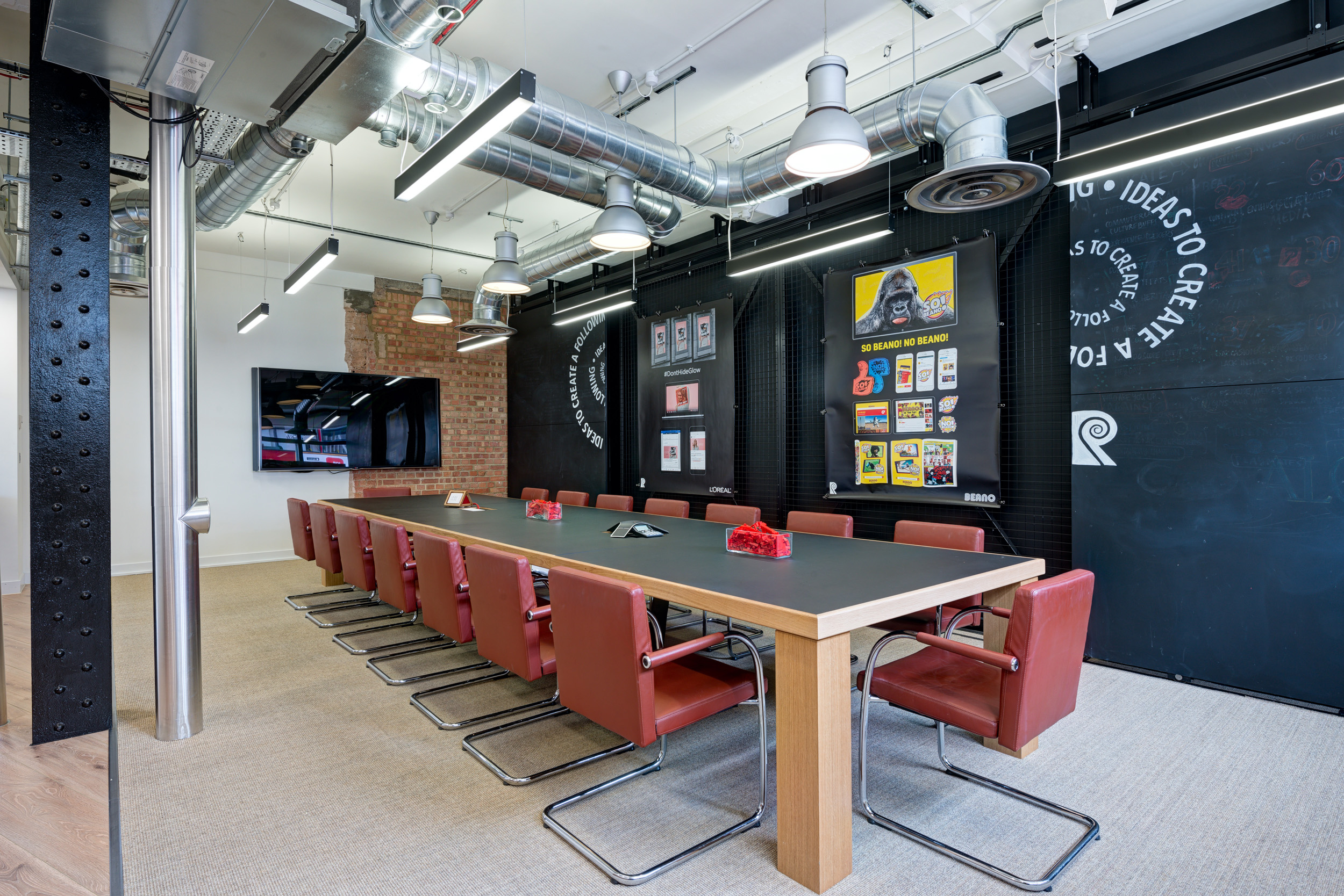 The Red Brick Road office meeting room features vibrant wall artwork and a sliding display wall for added versatility in presentations.