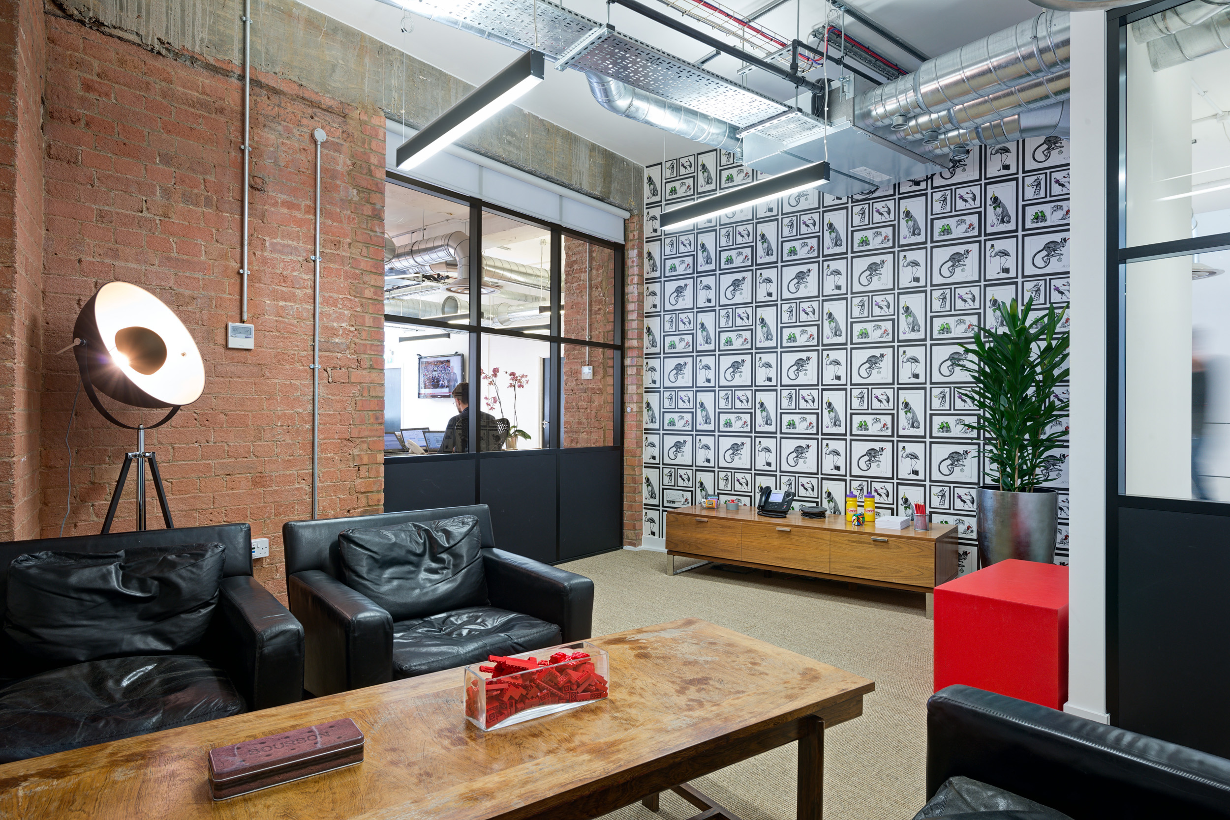 Breakout corner at Red Brick Road office, with black leather seating and unique decor against an exposed brick wall.