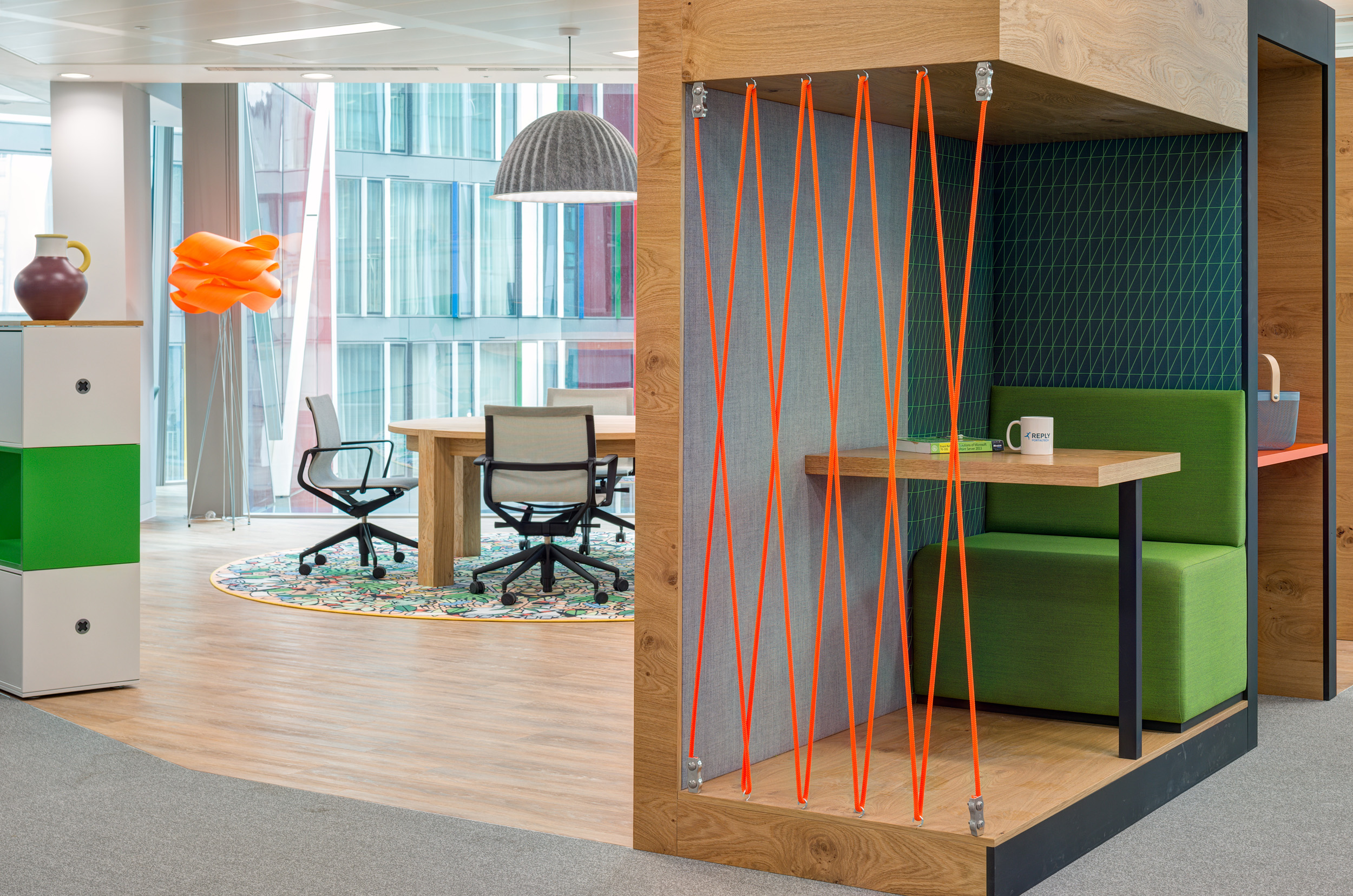 A creative nook within Reply's office, designed by Modus Workspace, showcasing green seating, orange accents, and modern decor for focused work.