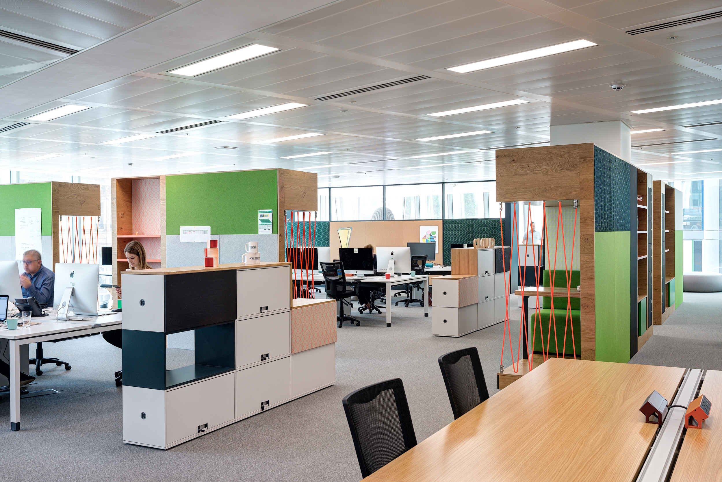 Open workspace design in Reply's office by Modus Workspace, with functional desk arrangements, colourful dividers, and ample natural light for a dynamic work environment.