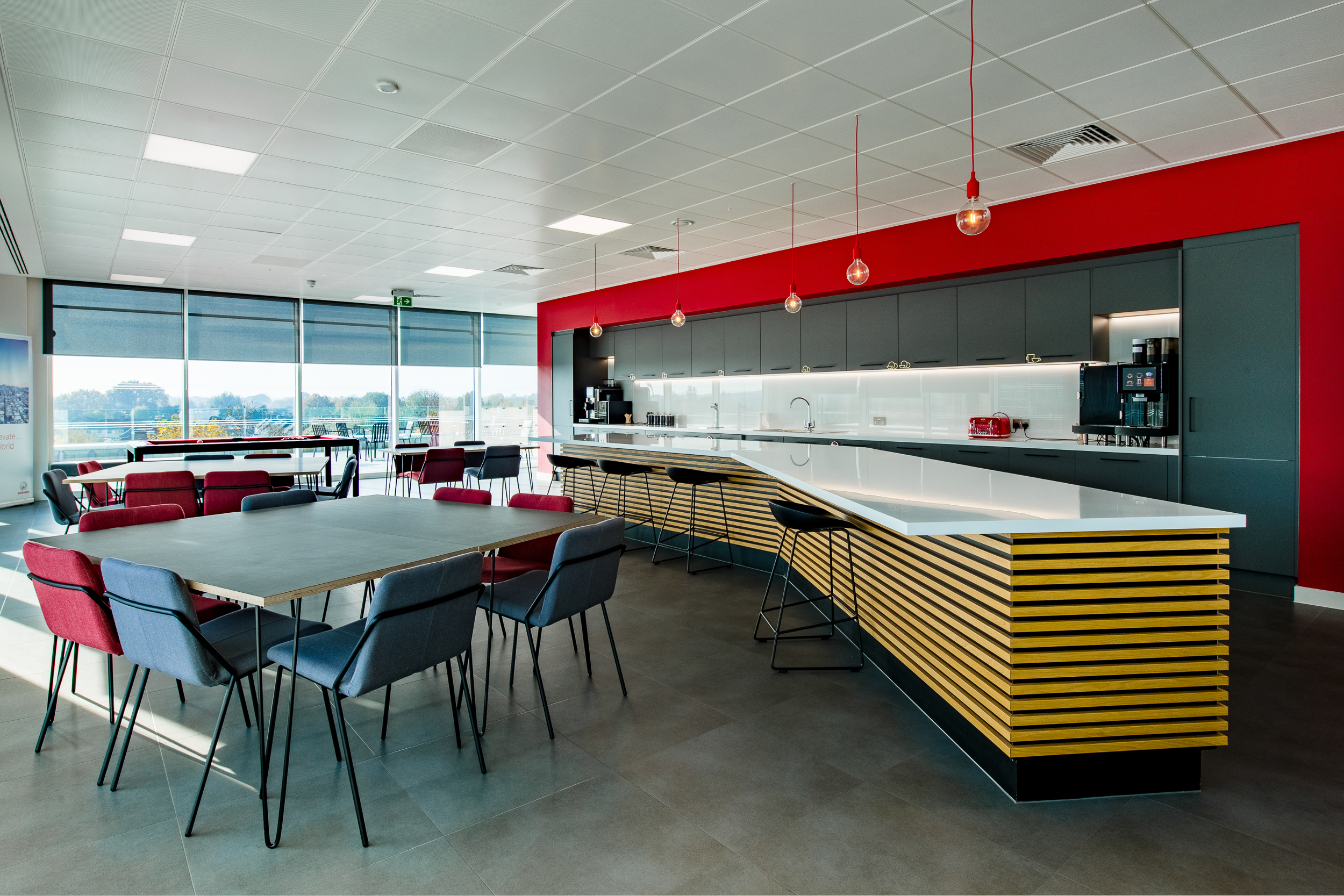 Spacious teapoint area at Schindler Group's Weybridge office, featuring modern seating and ample natural light, designed to encourage employee interaction