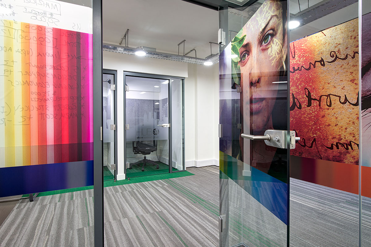 Phone booths in Shaw Contract Group's Clerkenwell showroom, featuring glass walls with bold, colourful graphic designs for a creative workspace.