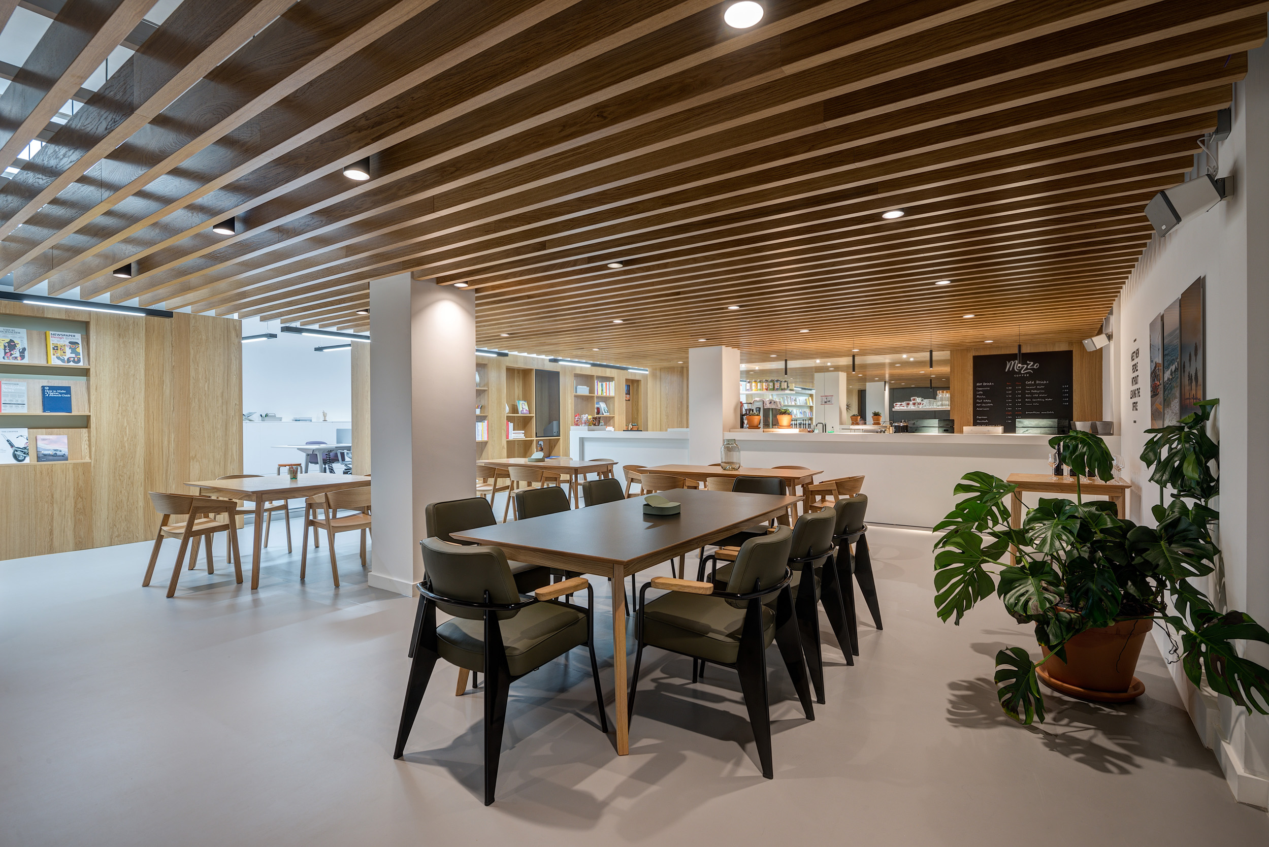 A teapoint and breakout seating area with wooden tables and chairs, beneath a wooden slatted ceiling in Spaces Epworth House.