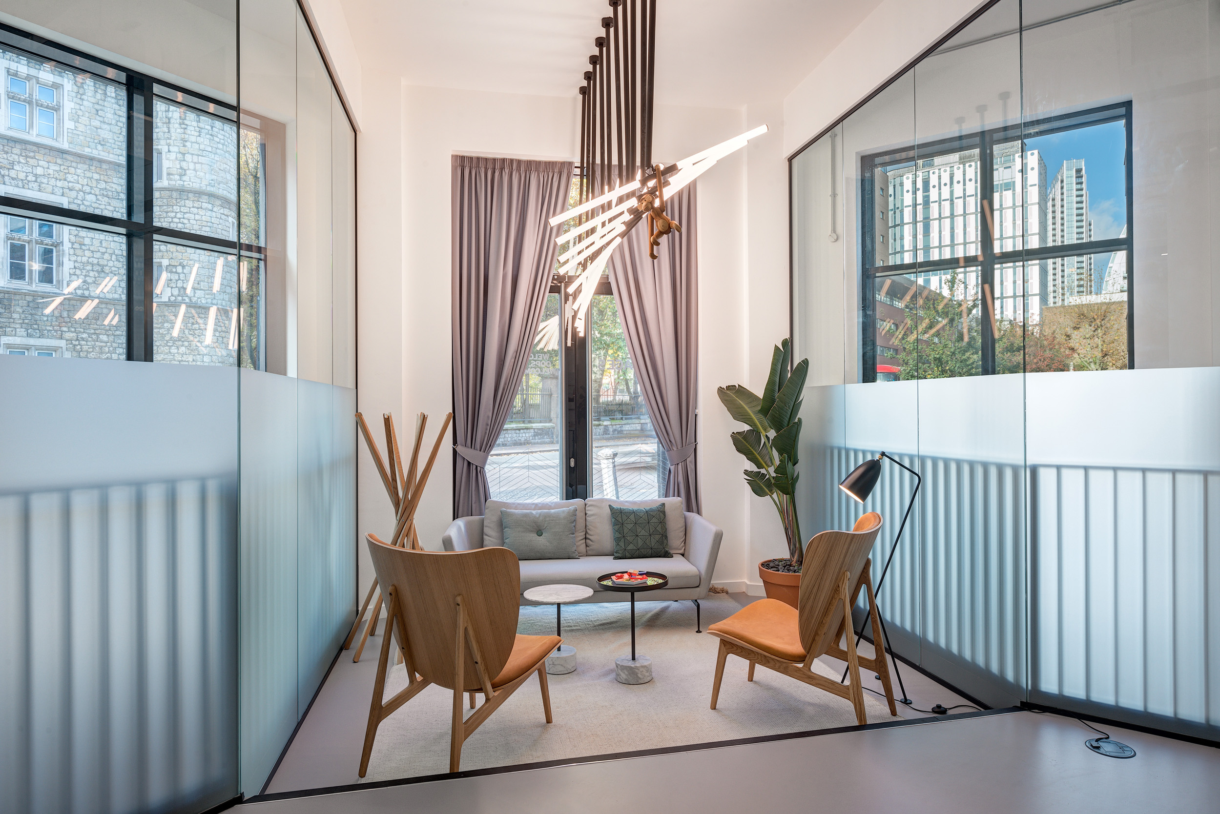 A glass-enclosed lounge area with soft seating and stylish decor overlooking a large window in Spaces Epworth House.
