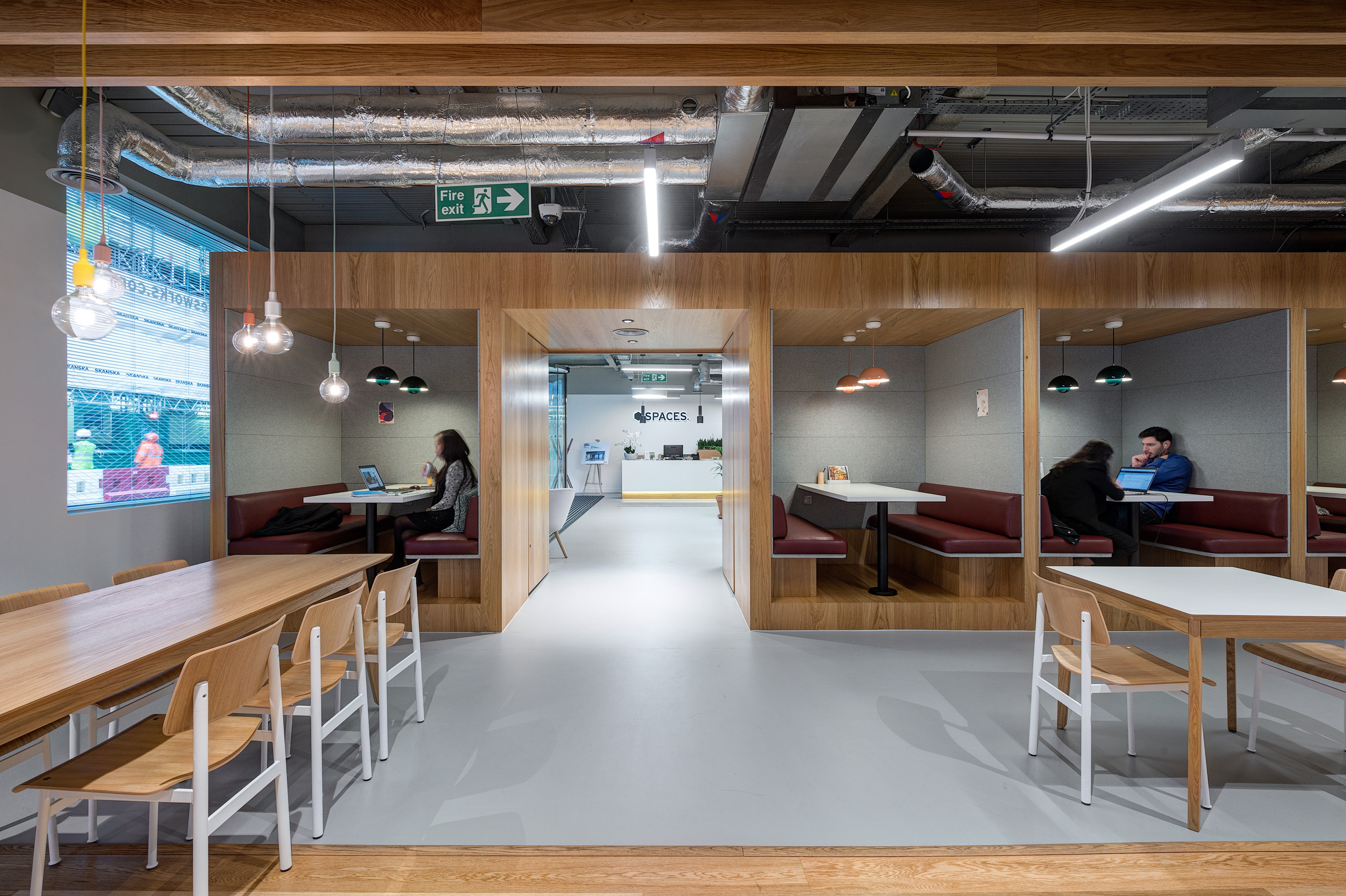 Semi-private booths with integrated lighting and wooden accents with maroon leather seating.
