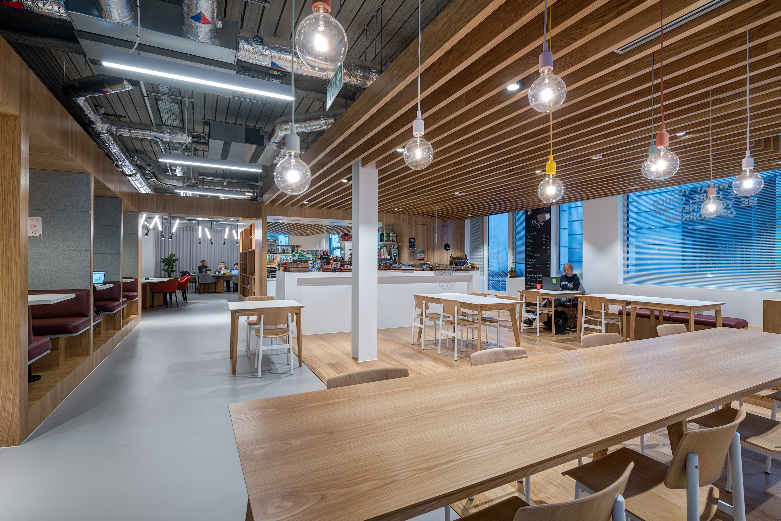 A bright cafe area with wooden ceilings, multiple seating options, and a bar counter at Spaces, 30 Moorgate.