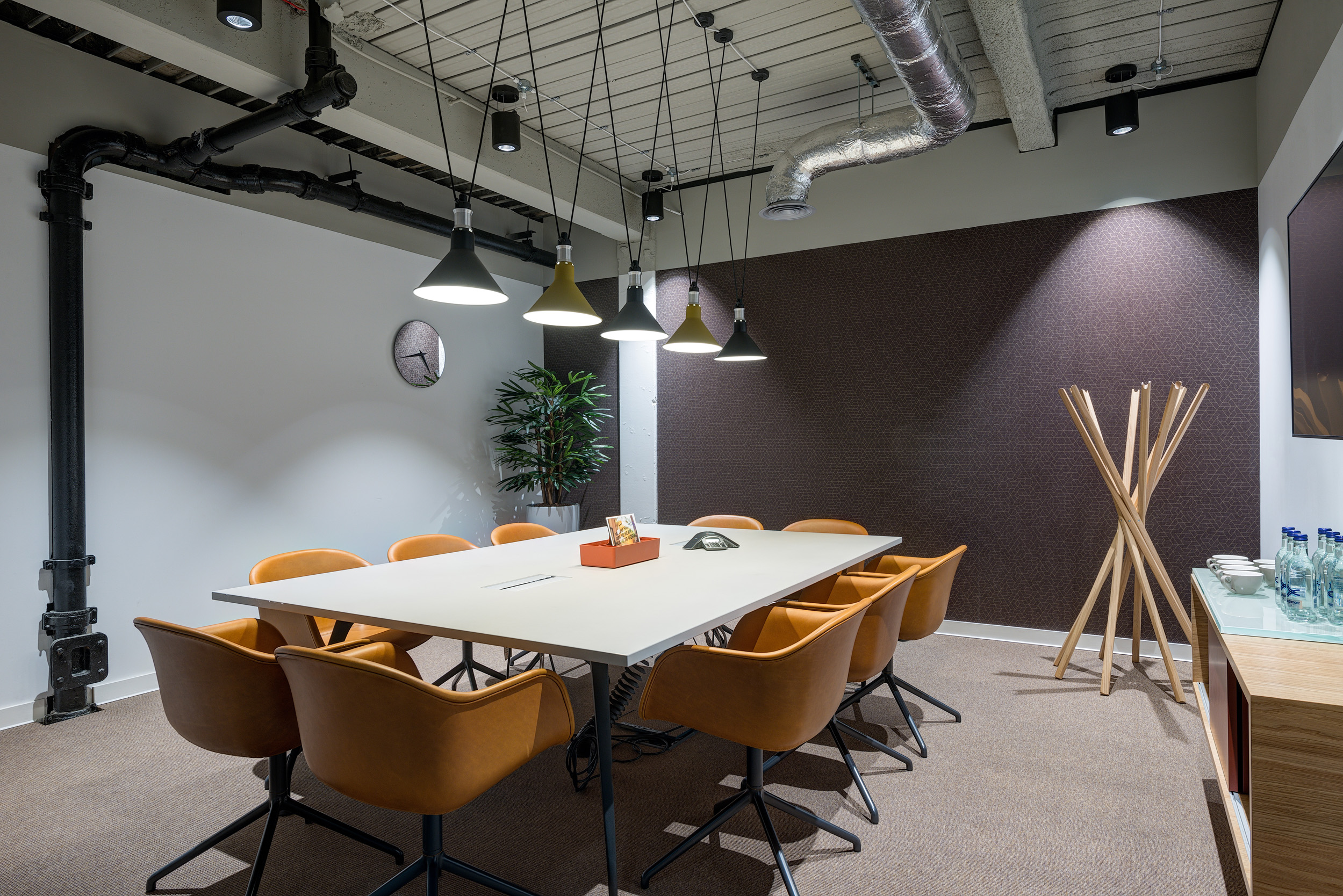 A meeting room featuring yellow chairs, a long table, and overhead lights, with exposed ductwork at Spaces, 30 Moorgate.
