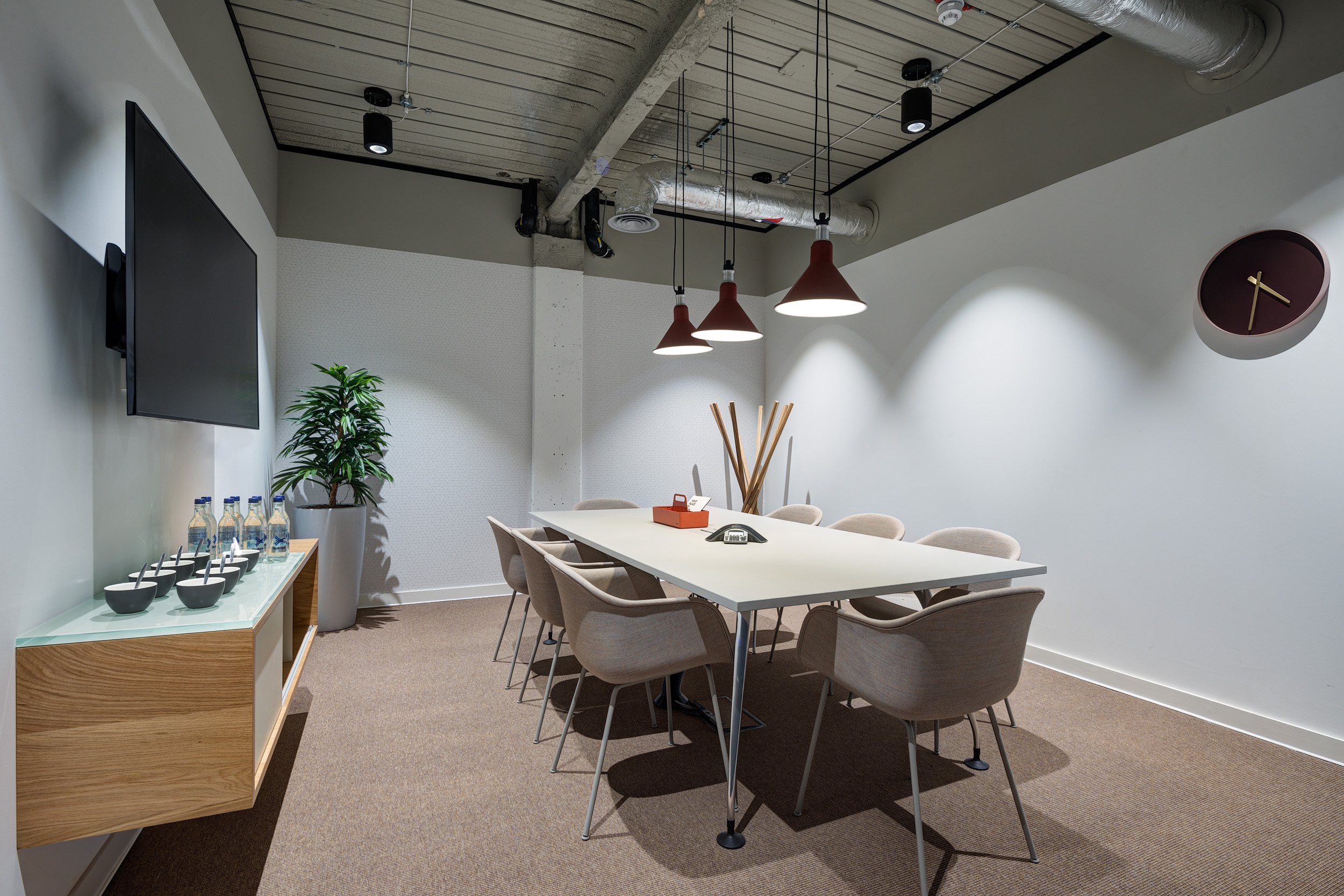 A minimalist meeting room with neutral tones, a large TV screen, and ceiling lighting at Spaces, 30 Moorgate.