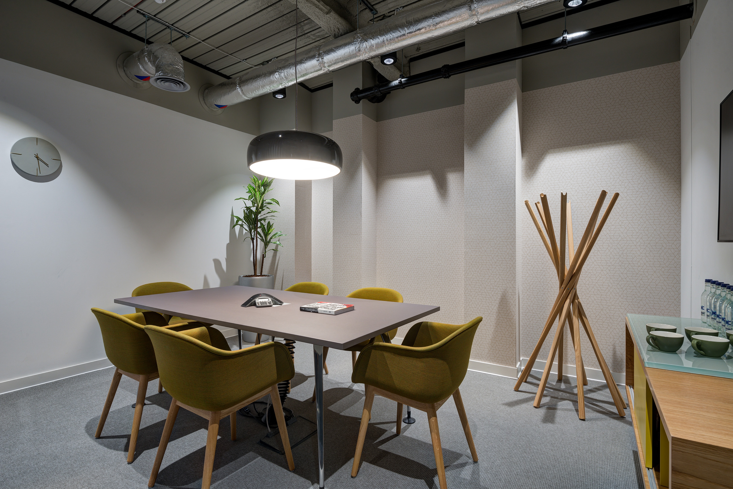 A small meeting room with green chairs, a table, and industrial-style lighting at Spaces, 30 Moorgate.